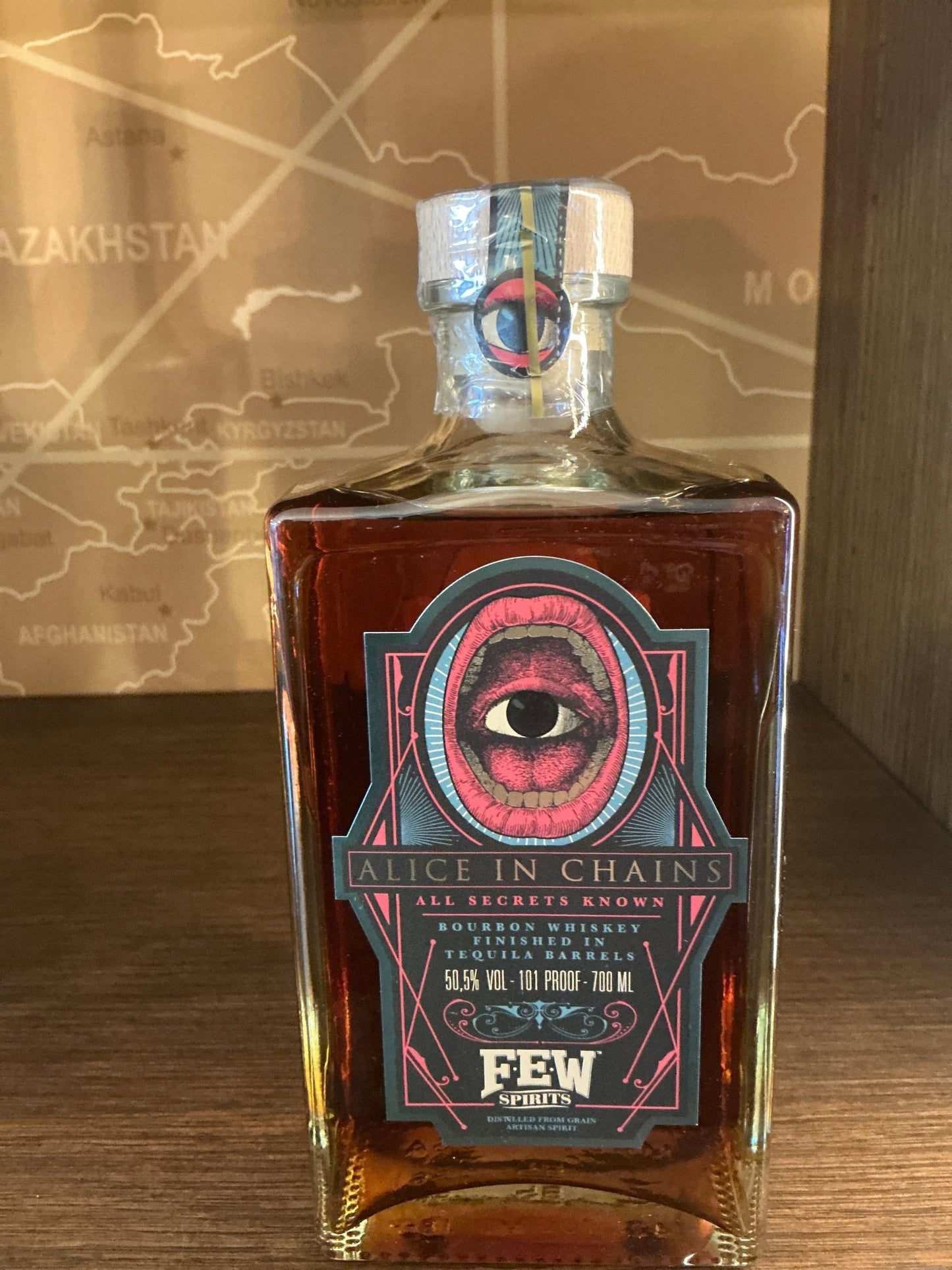 FEW ‘Alice in Chains’ Bourbon in a square glass bottle with dark amber liquid, label featuring a red eye graphic and.