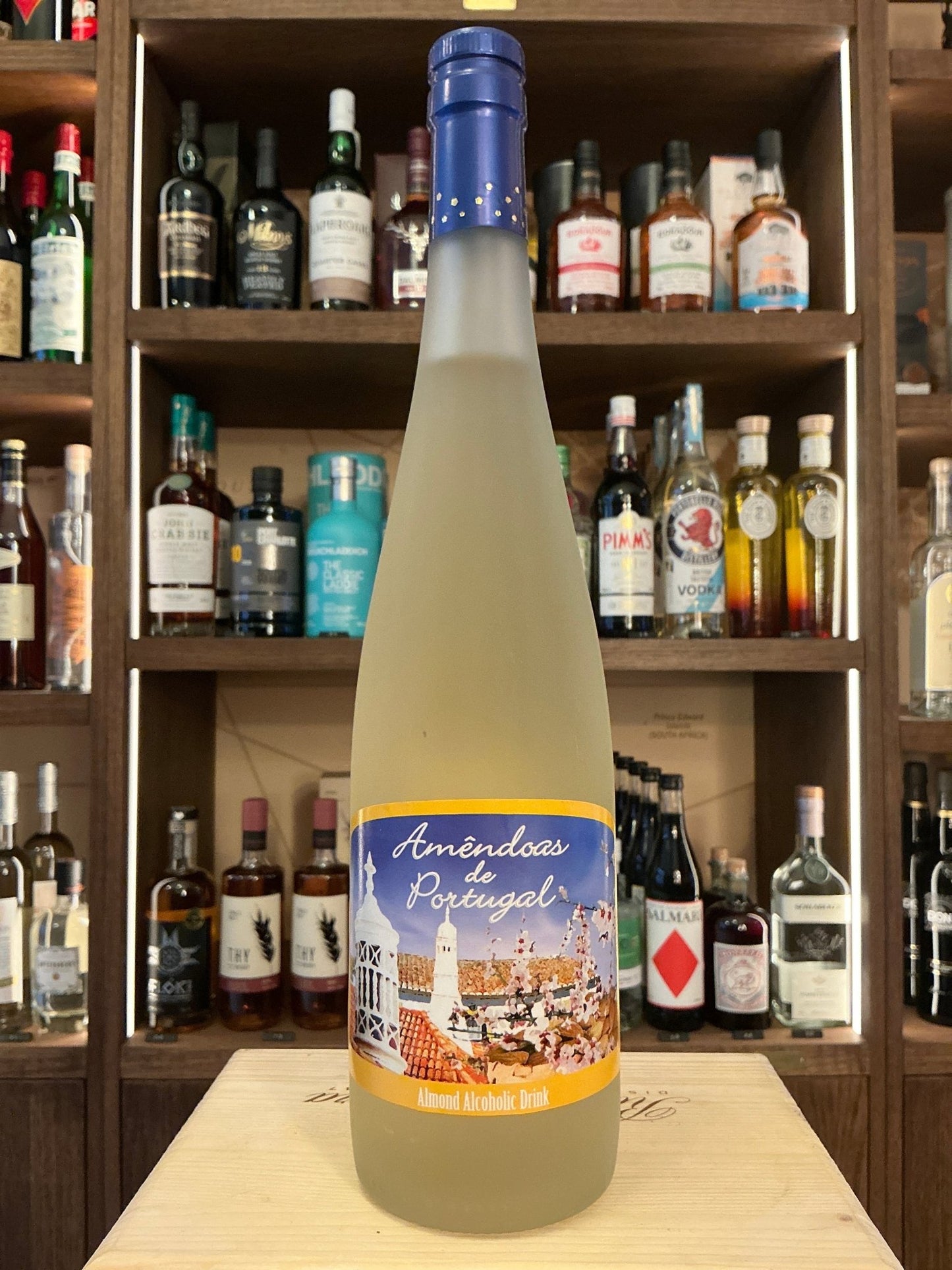 Frosted glass bottle of Amendoas De Portugal almond liqueur with blue cap and detailed label, artisan small-batch specialty.