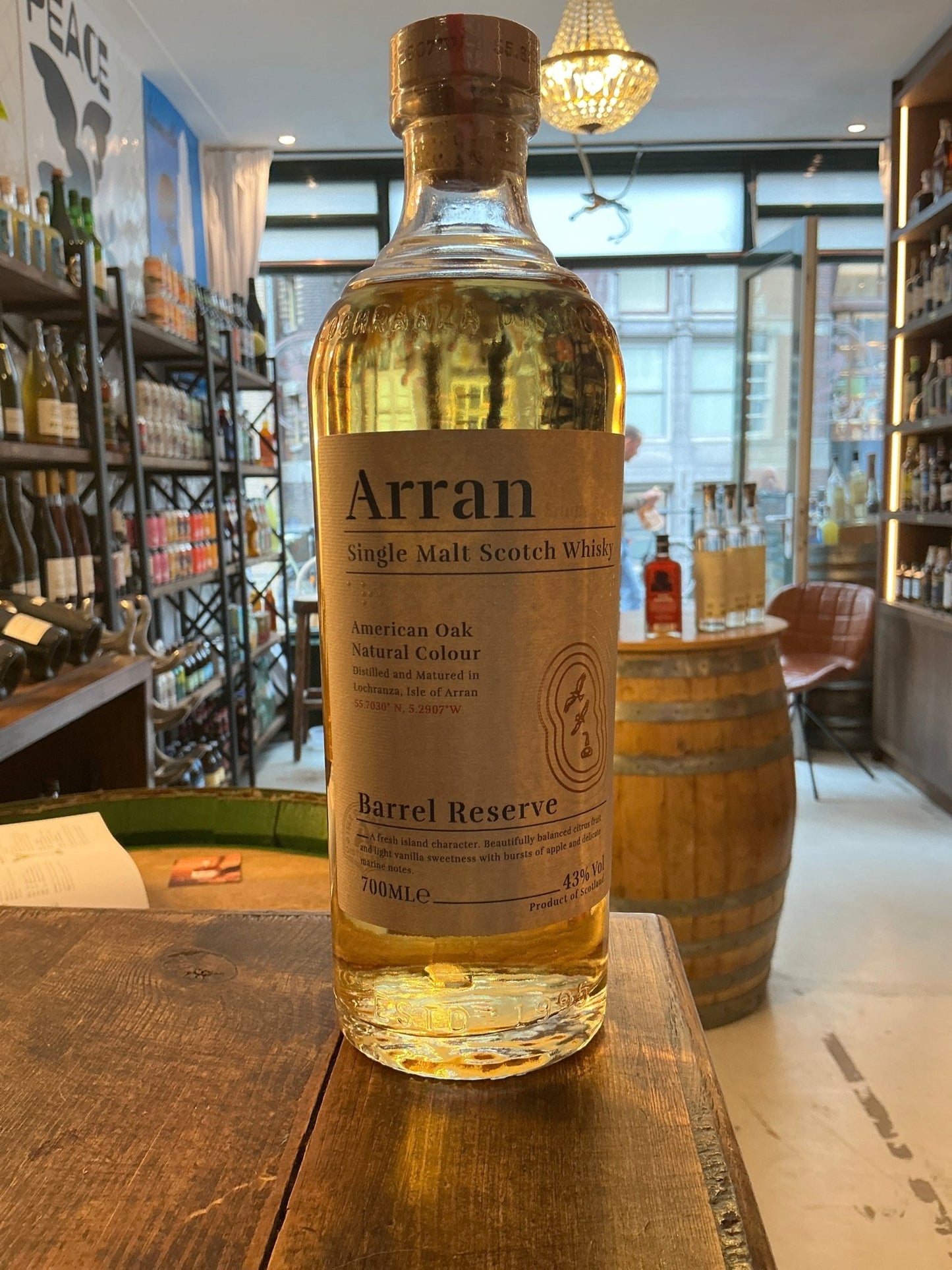 Arran Barrel Reserve single malt Scotch whisky bottle with golden amber liquid, premium aged artisan spirit in a distillery.