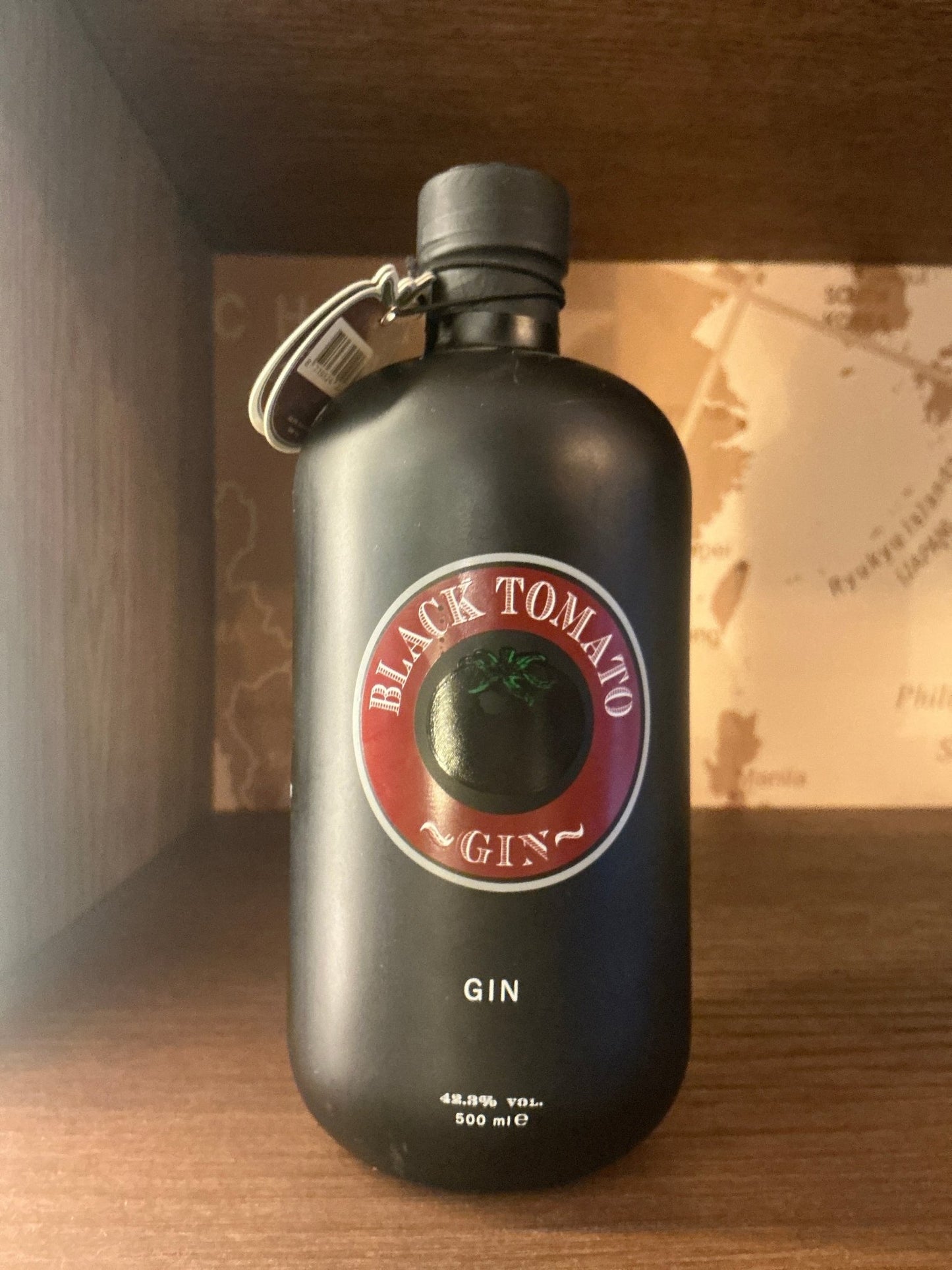 Matte black bottle of Black Tomato Gin with round red label featuring tomato graphic, premium distilled artisan Dutch gin.