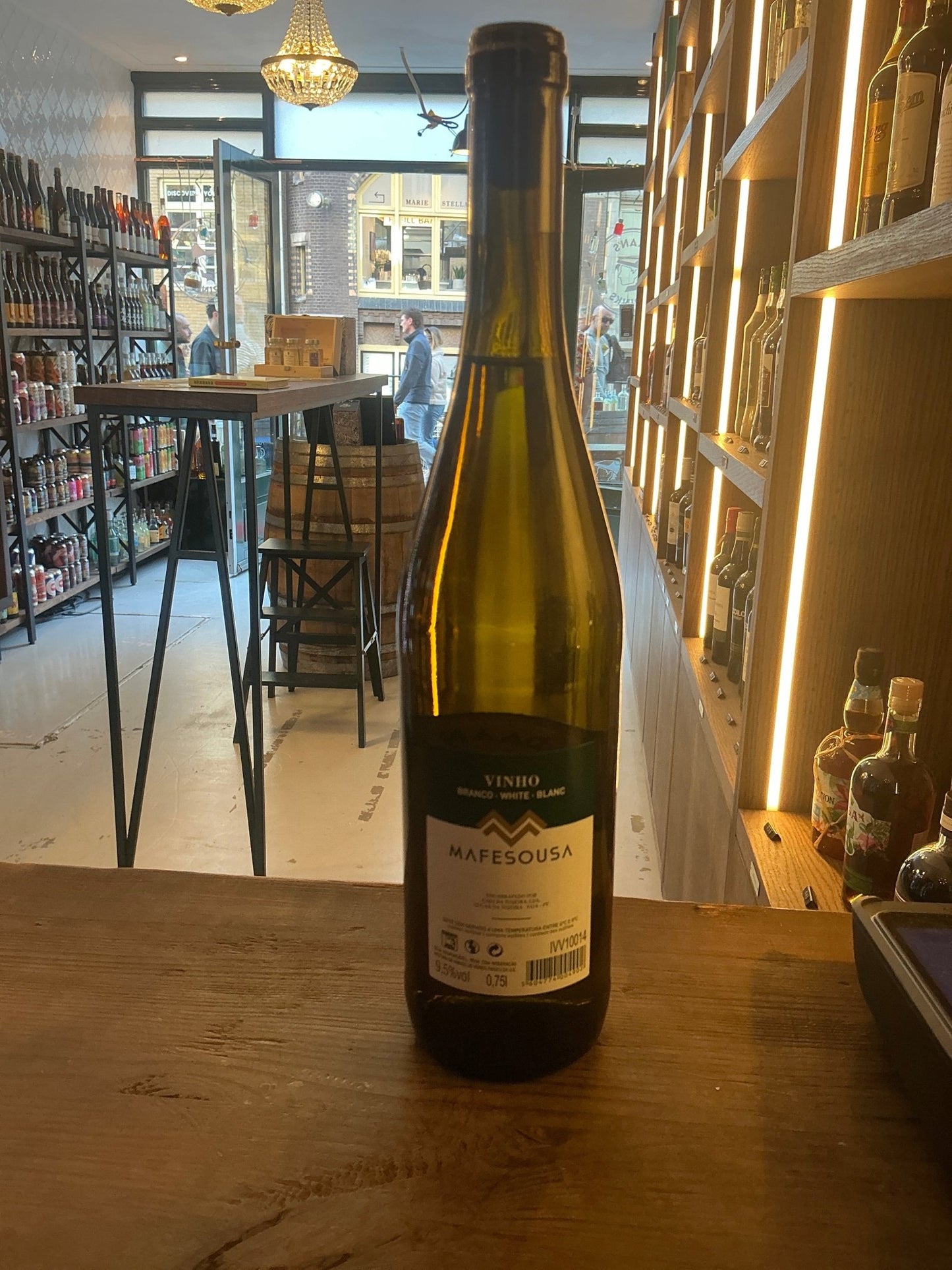 Tall green glass bottle of Casa da Tojeira Mafesousa 2023 Portuguese white wine with detailed label on a wooden counter in a .