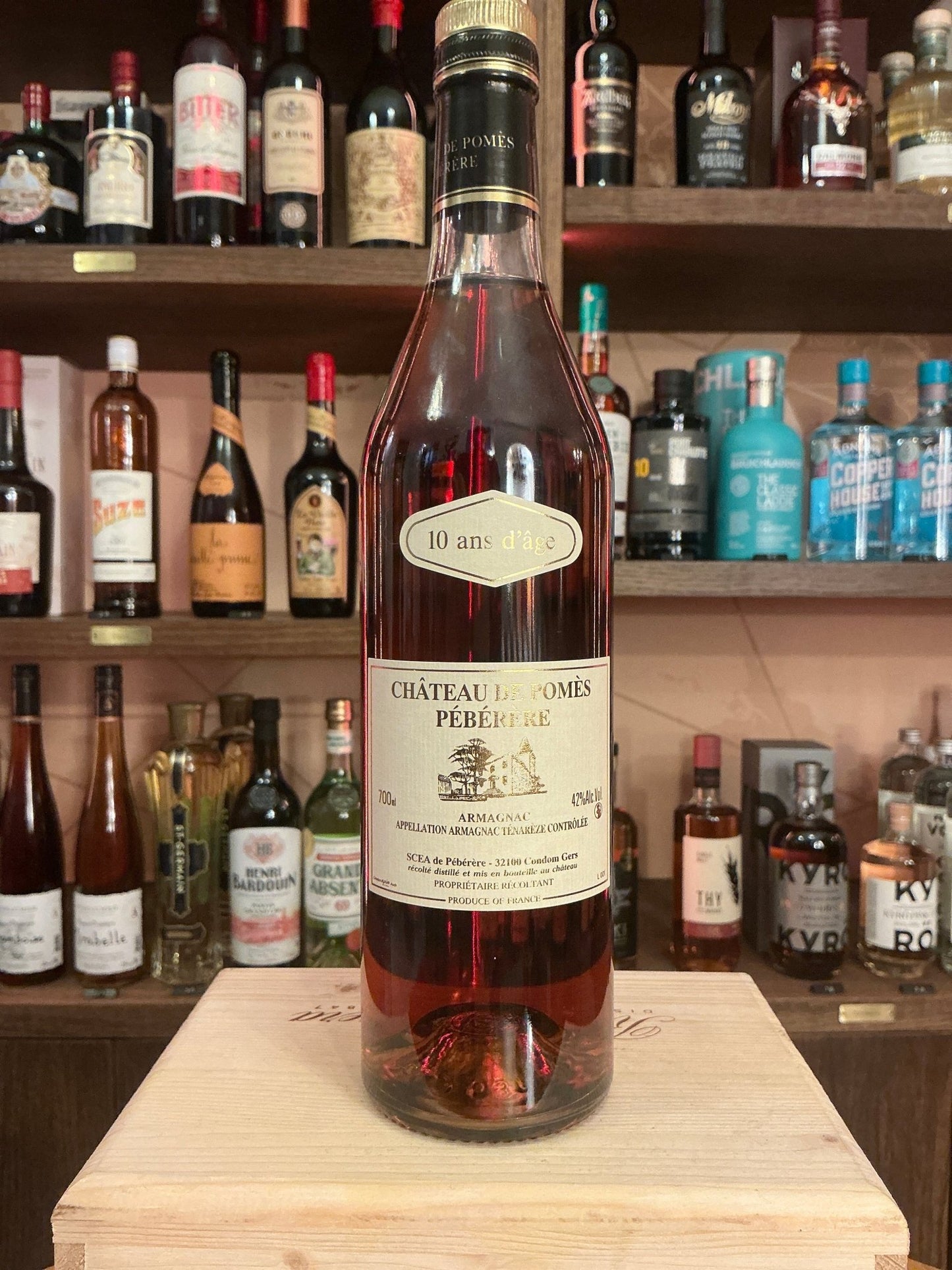 Château de Pomès Pébérère 10 Ans premium aged French Armagnac brandy bottle with detailed vintage label on wooden stand.