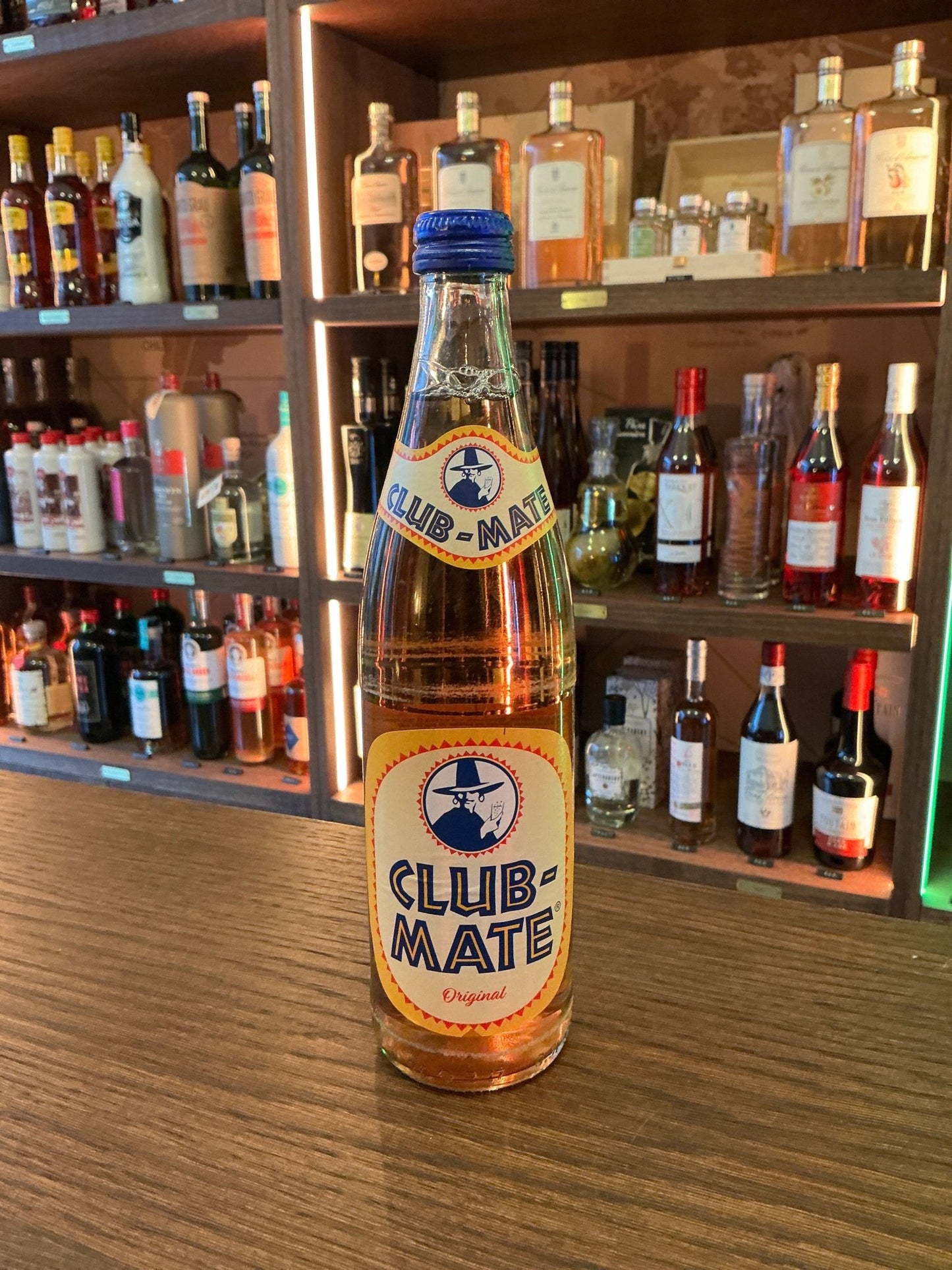 Club-Mate Original 500ml glass bottle with amber liquid, nestled among premium small batch craft spirits like gin, whisky,.