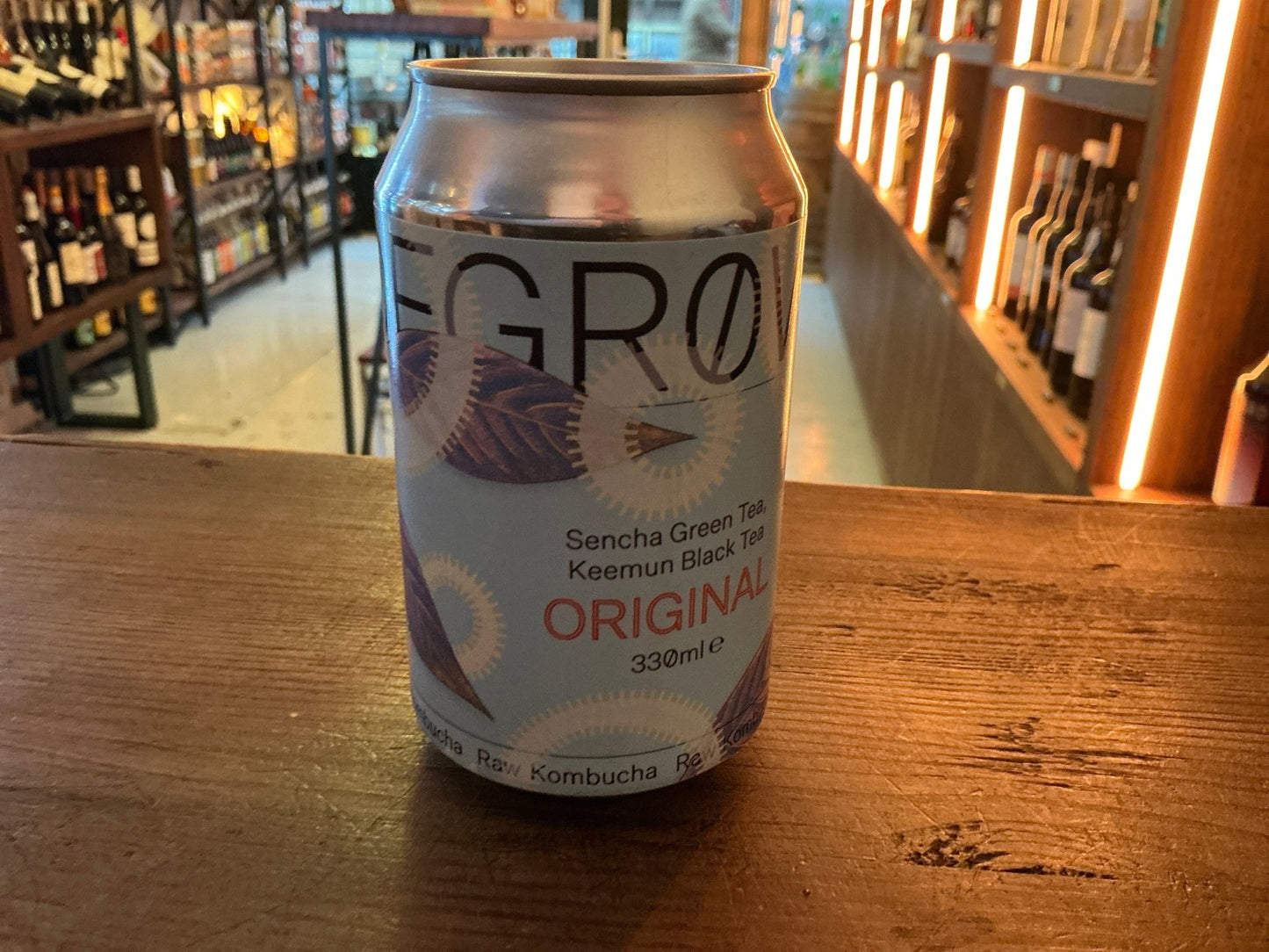 Degrow Lab Original Sencha Green Tea & Keemum kombucha can with botanical-inspired label on wooden table in artisan spirits.