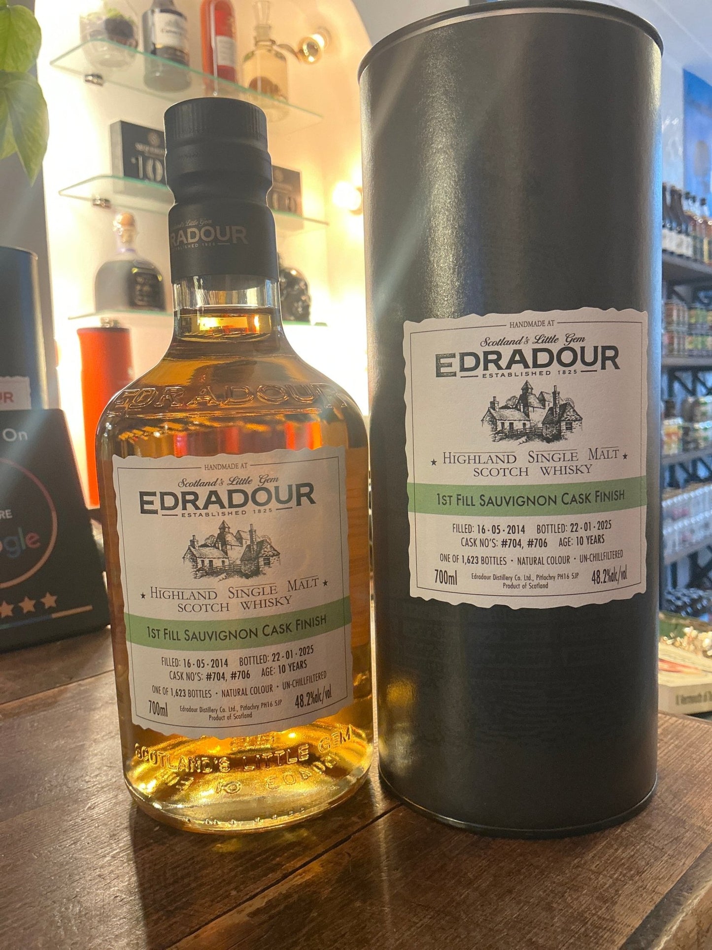 Edradour 2014 Sauvignon single malt whisky bottle with amber liquid and black cap, next to matte black cylindrical box with.
