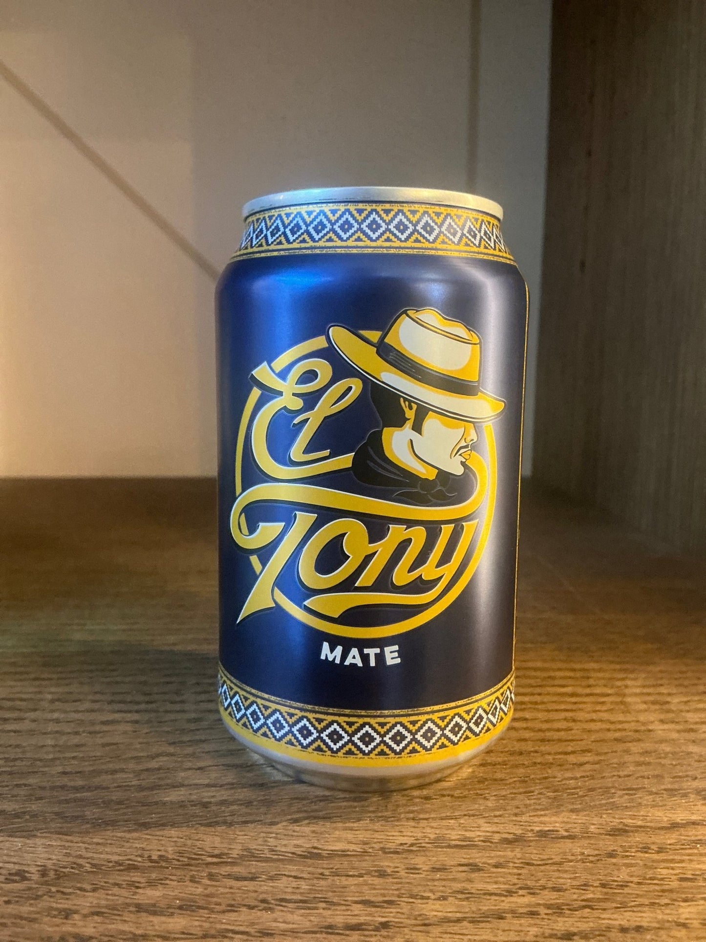 Matte black soda can with gold lettering featuring a stylized man in a fedora, ornate Dutch-inspired border on top and.