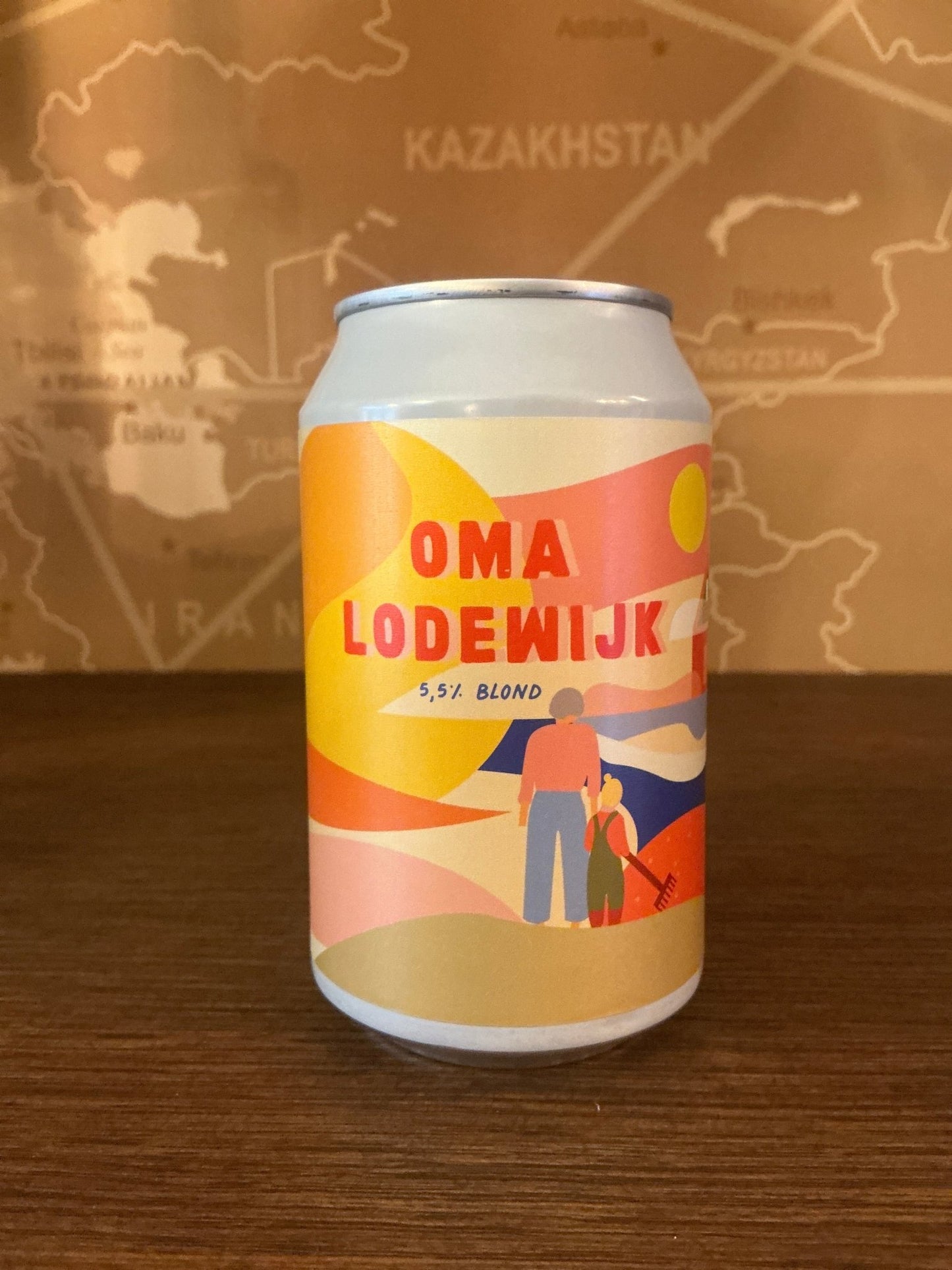 White aluminum can with a colorful, modern label featuring warm tones of yellow, orange, and pink, displaying the name "Oma.
