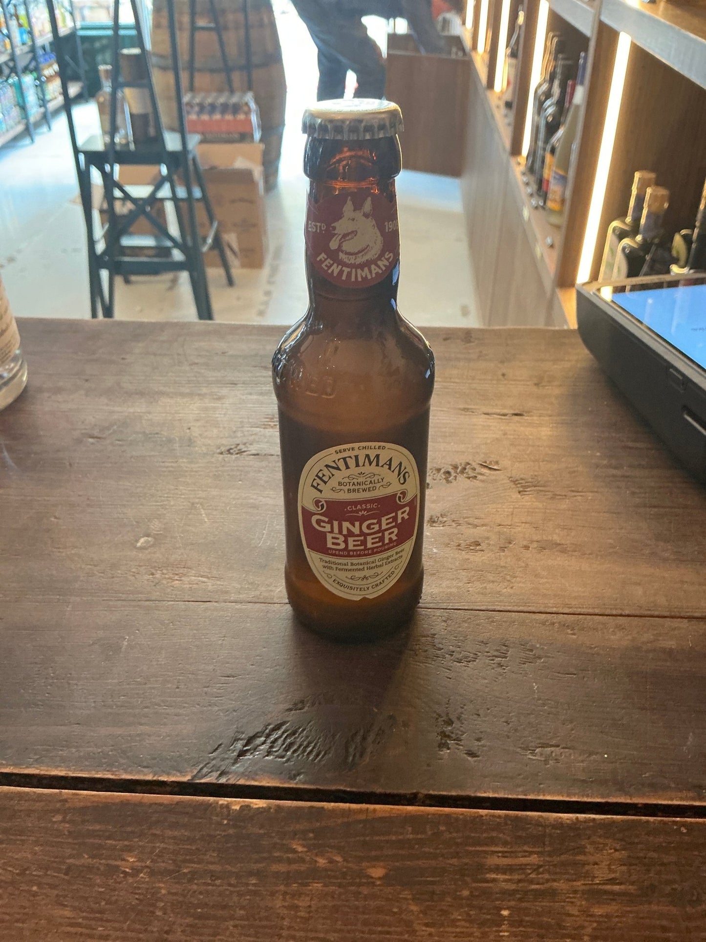 Fentimans Ginger Beer brown glass bottle with botanical spiced label on wooden table in artisan Dutch setting.