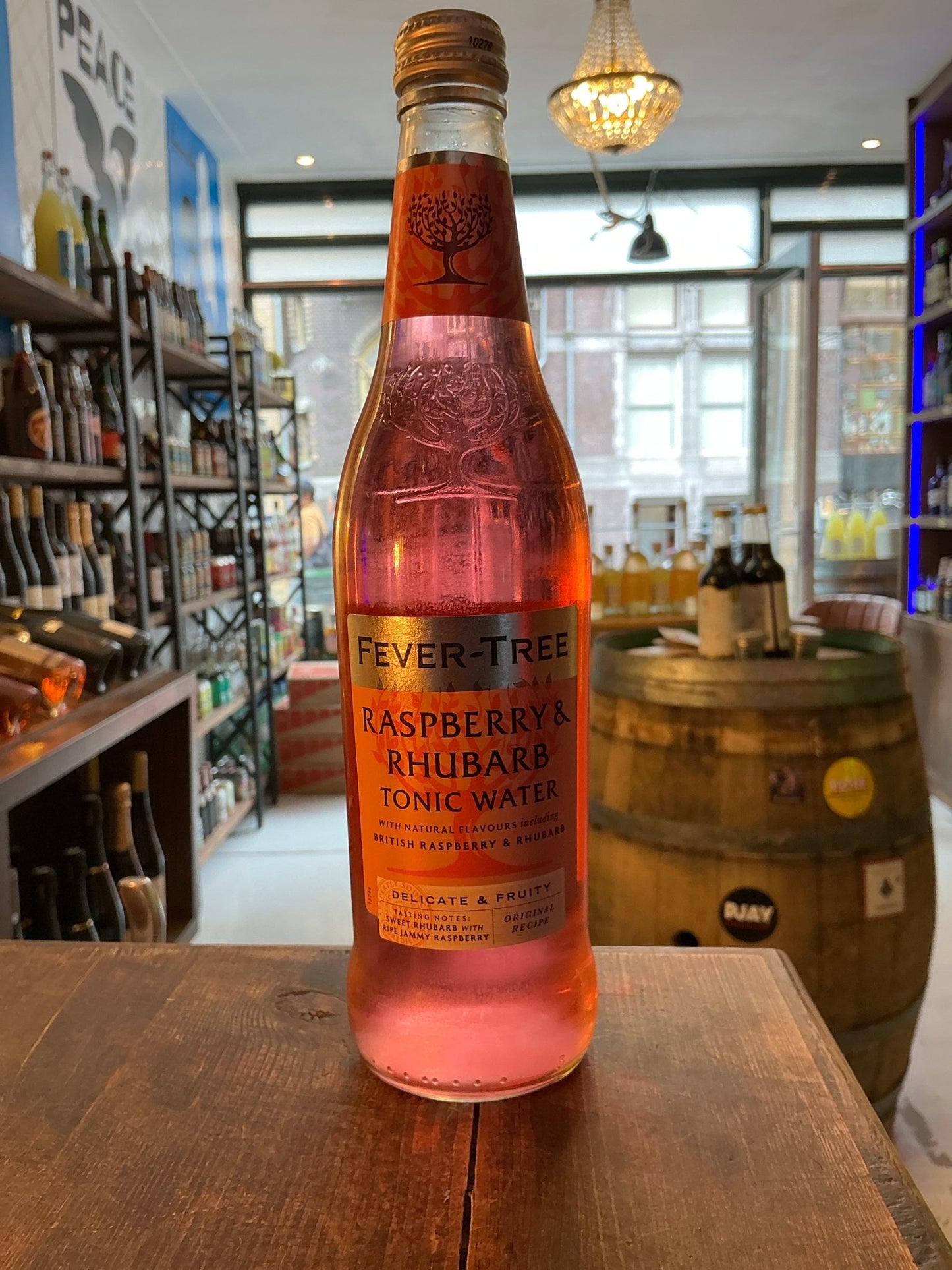 Fever Tree Raspberry and Rhubarb Tonic 50cl pink botanical spiced premium artisan bottle on wood table.