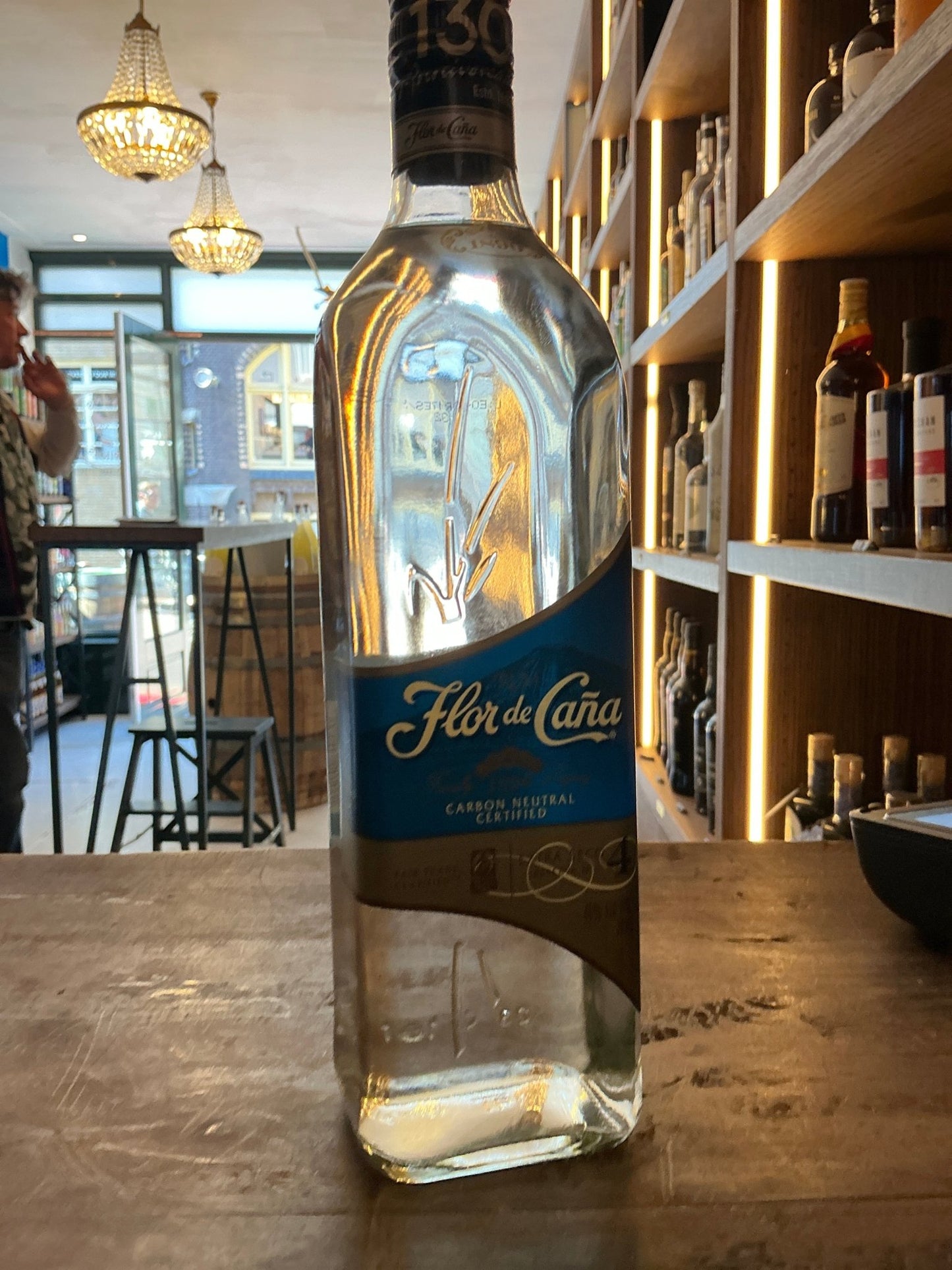 Flor de Caña 4 Year Aged Rum bottle with blue label on wooden table in artisan bar setting.