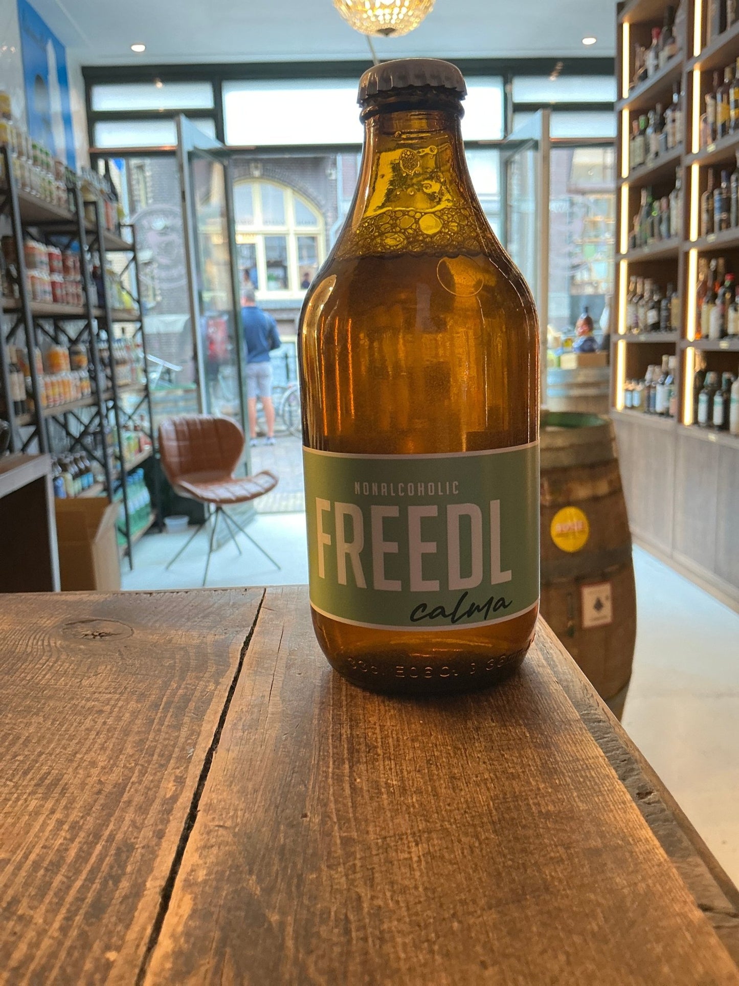 Amber glass bottle of FREEDL Calma non-alcoholic craft beer with green label, artisan Dutch small batch specialty spirits on .