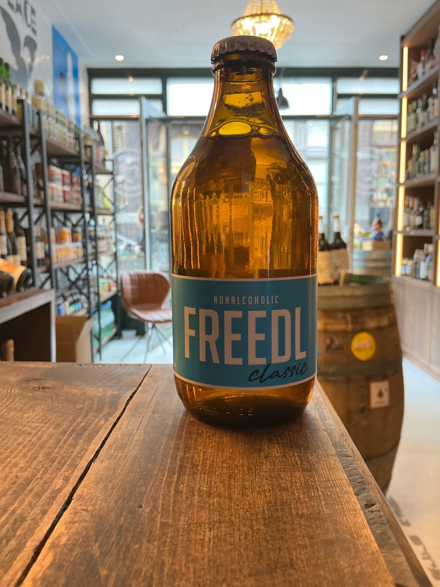 Amber craft beer bottle labeled FREEDL Classic on a wooden table in a rustic artisan store setting.