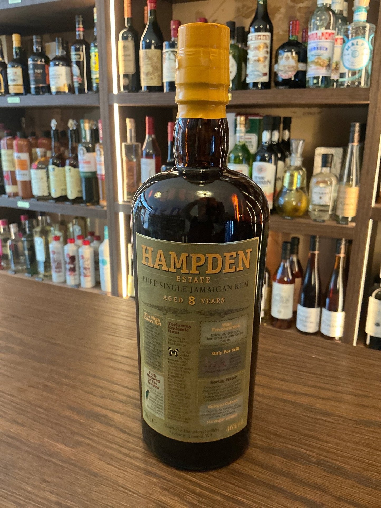 Hampden Estate Pure Single 8 Yr Jamaican Rum bottle with yellow wax seal, premium aged distilled spirit on wooden bar counter.