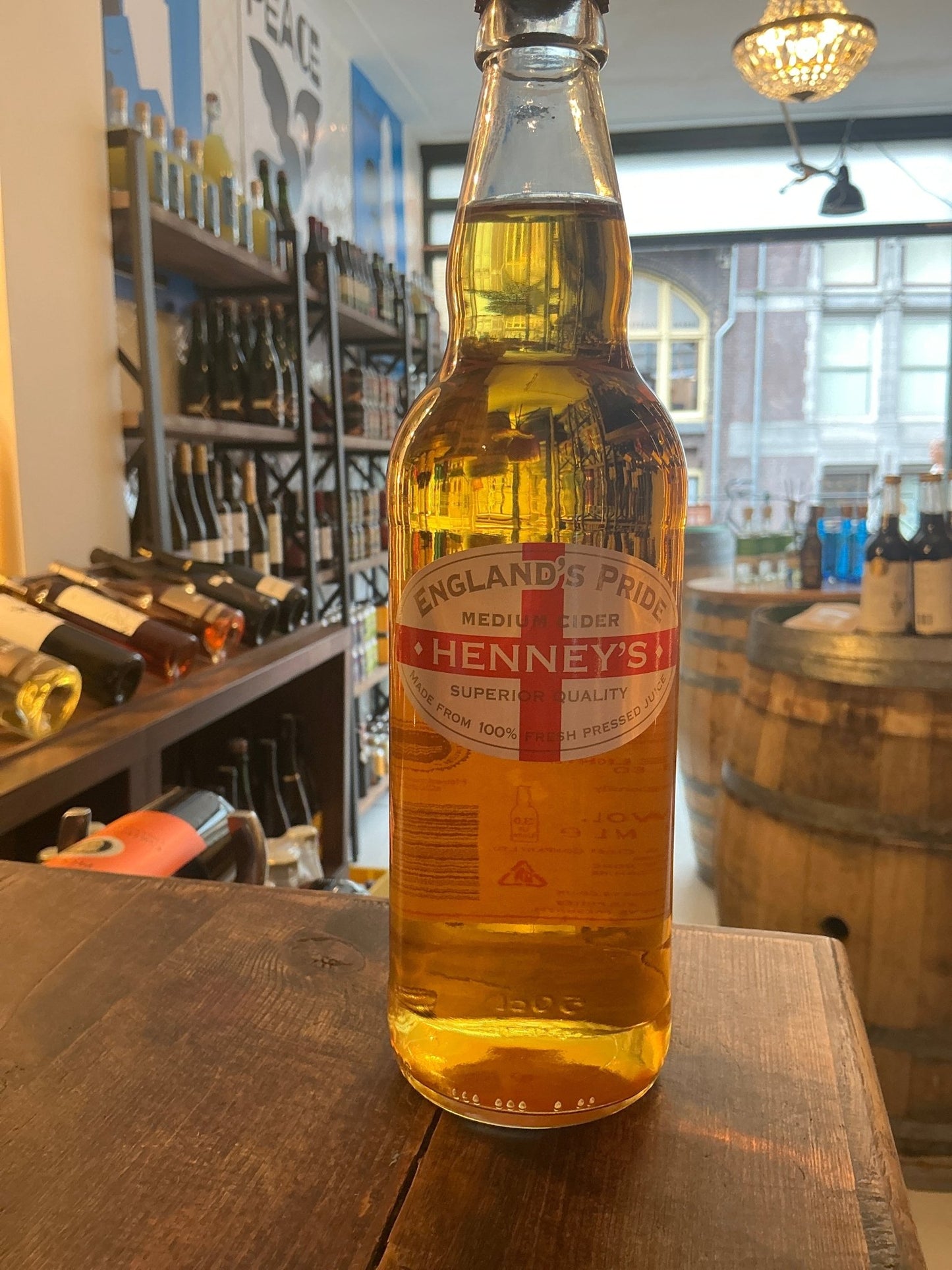 Henney’s England’s Pride Medium Cider bottle with golden amber liquid, premium artisan cider in glass bottle on rustic.