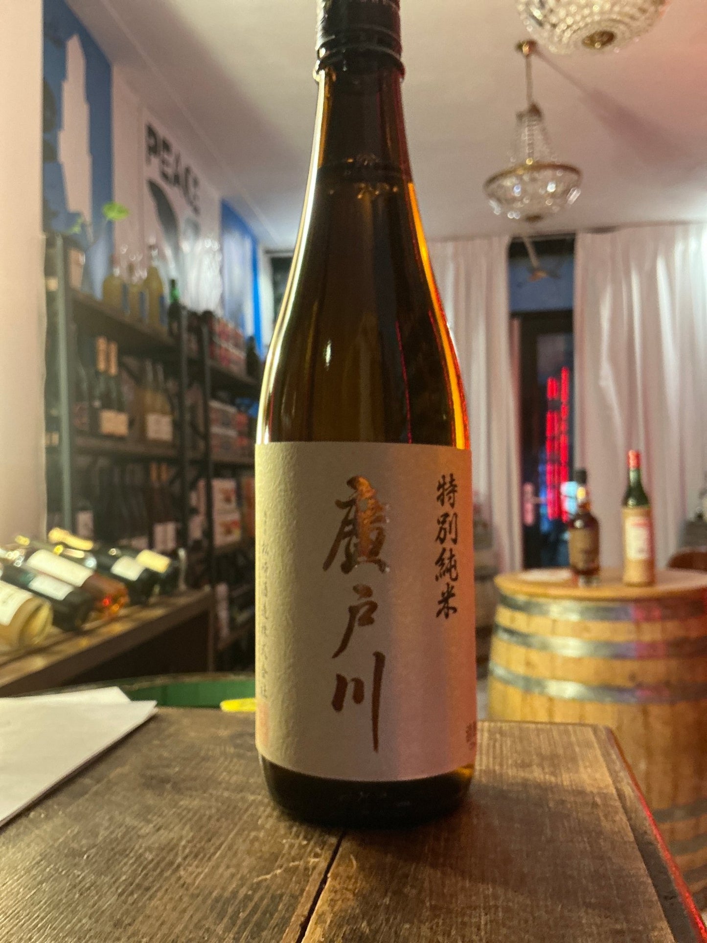 Hirotogawa Tokubetsu Junmai premium sake bottle with minimalist beige label and black Japanese calligraphy on wooden table.