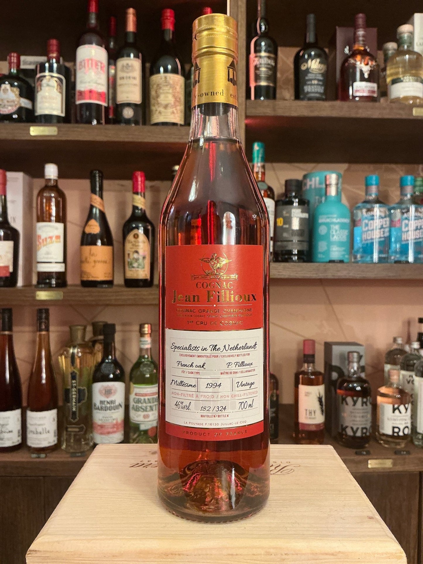 Jean Fillioux Single Cask 1994 aged French cognac bottle with rich amber liquid on wooden surface, surrounded by premium.
