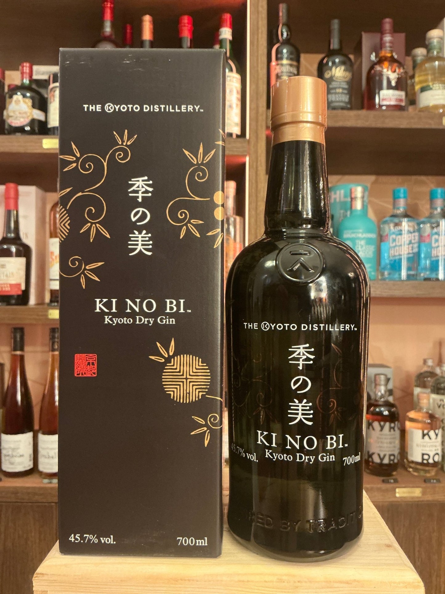 Ki No Bi Kyoto Dry Gin black glass bottle with gold botanical accents and matching elegant black box on wooden bar shelf,.