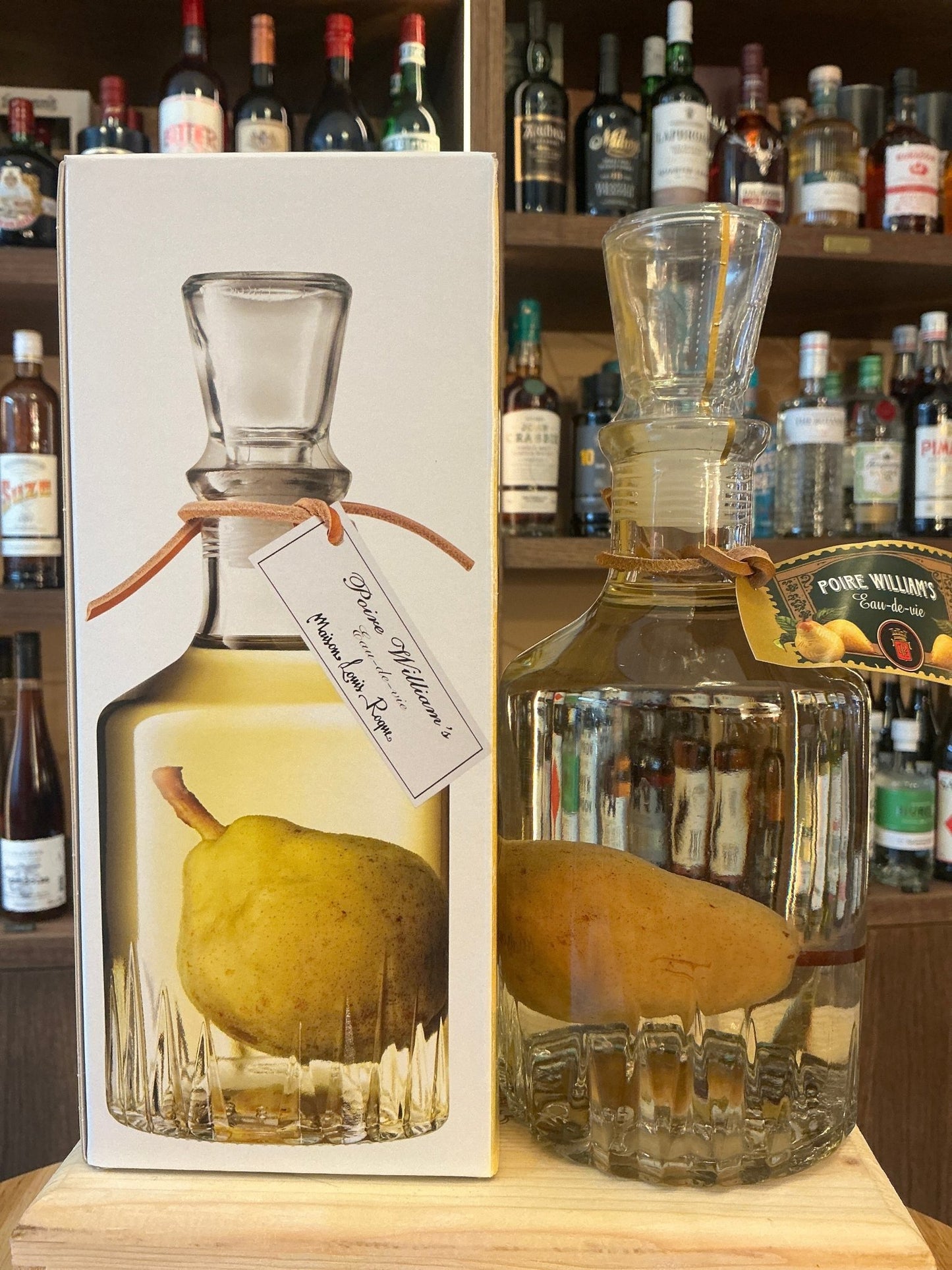 Maison Louis Roque Poire Williams premium fruit brandy bottle with ripe pear inside, artisan distilled specialty spirit.