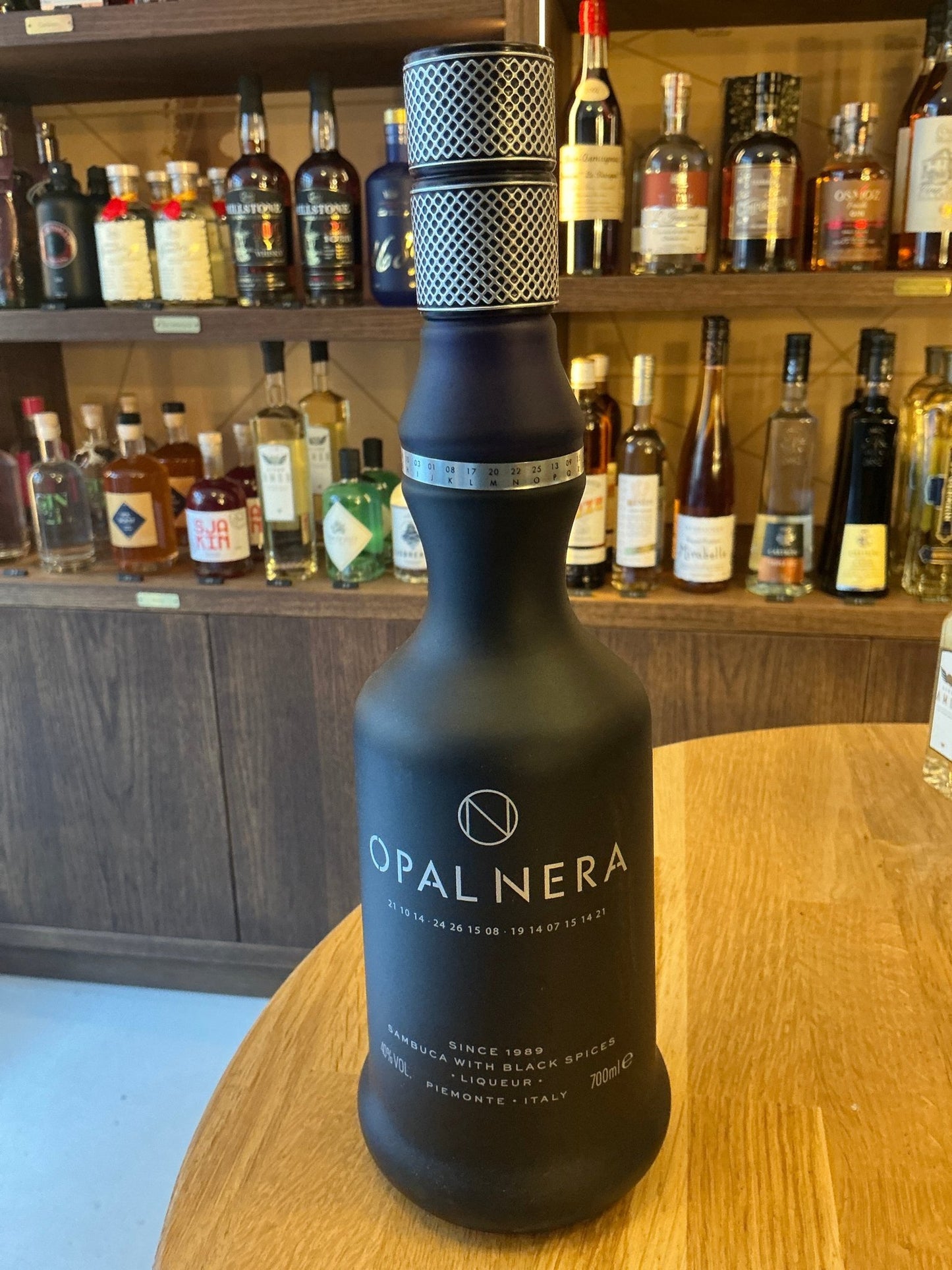 Matte black bottle of Opal Nera Sambuca with elegant white and silver lettering, premium Dutch artisanal liqueur, sealed.