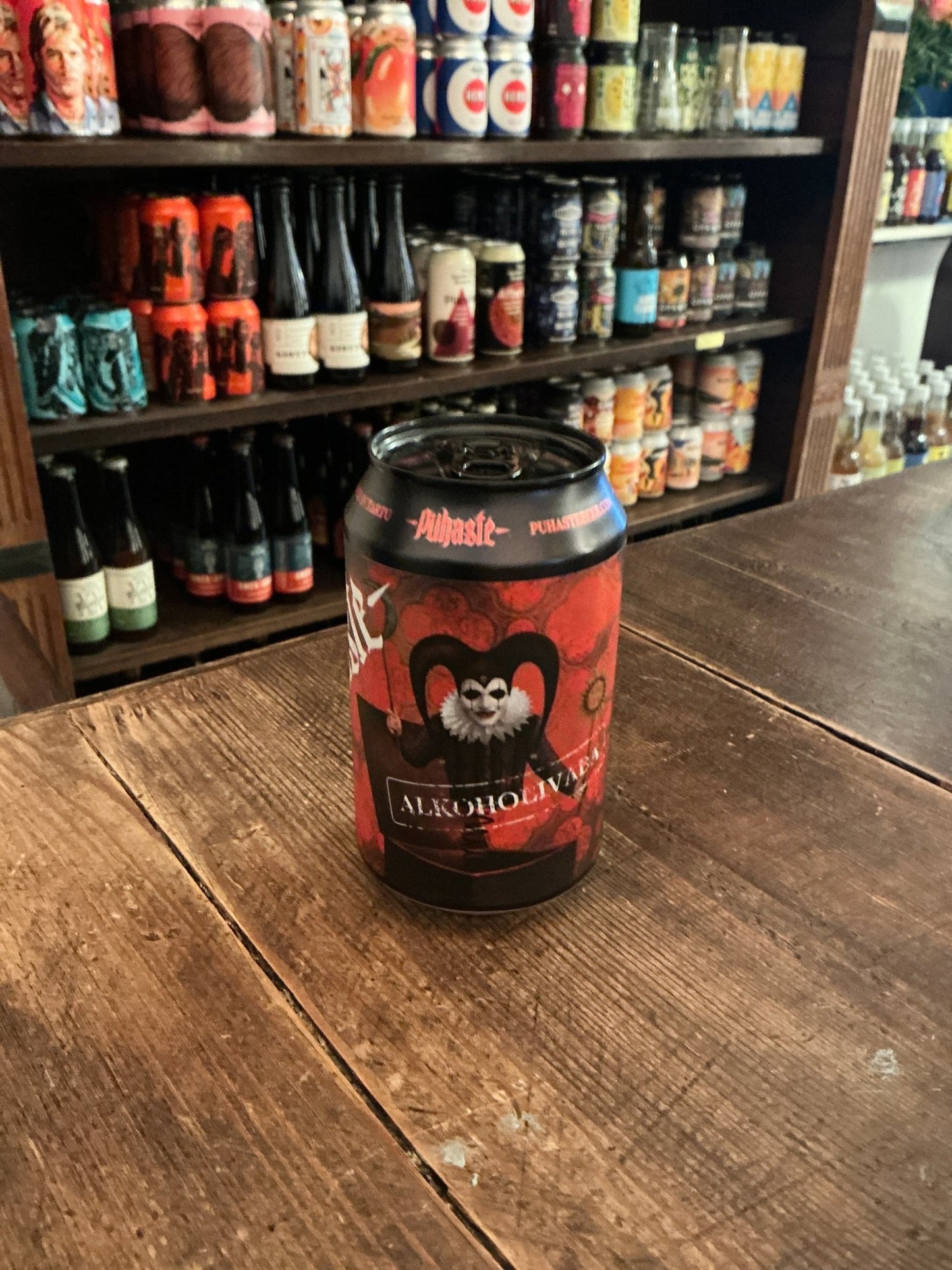 Red and black Pühaste Jokker non-alcoholic pale ale craft beer can with a playful jester design on a wooden table in front.