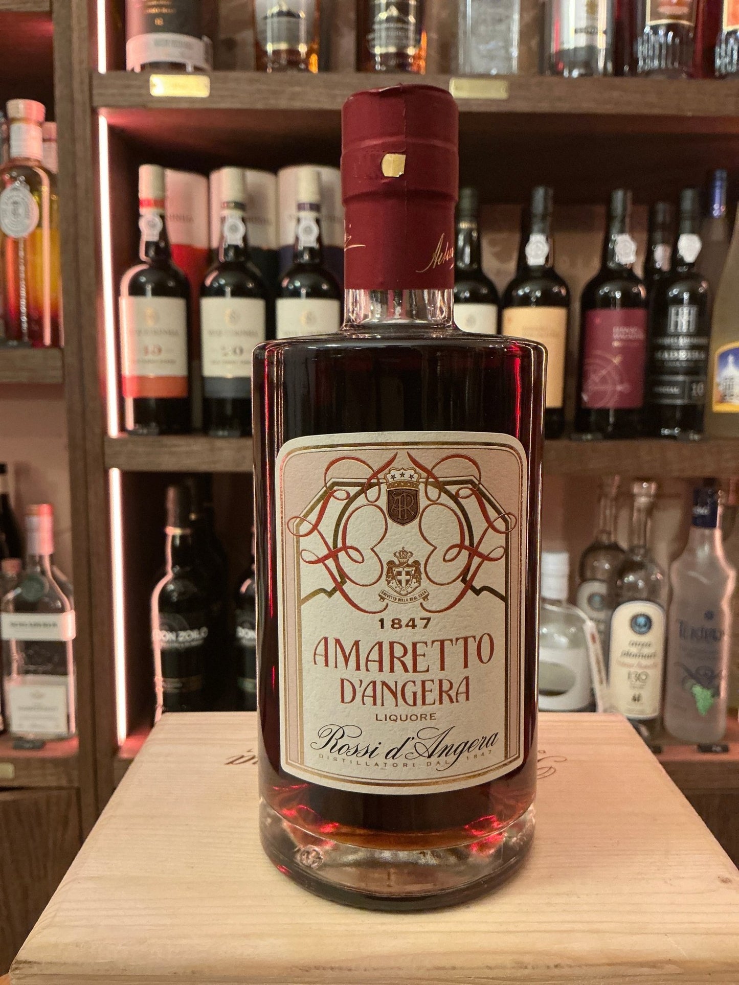 Rossi D'Angera Amaretto bottle with deep amber liqueur, premium artisan nut-flavored spirit in a clear glass bottle with red .