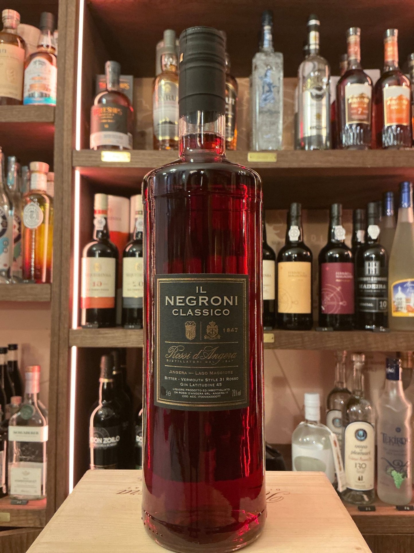 Rossi D'Angera Negroni Classico 1-liter bottle with deep red botanical gin and spiced liqueur blend on wooden shelf with.