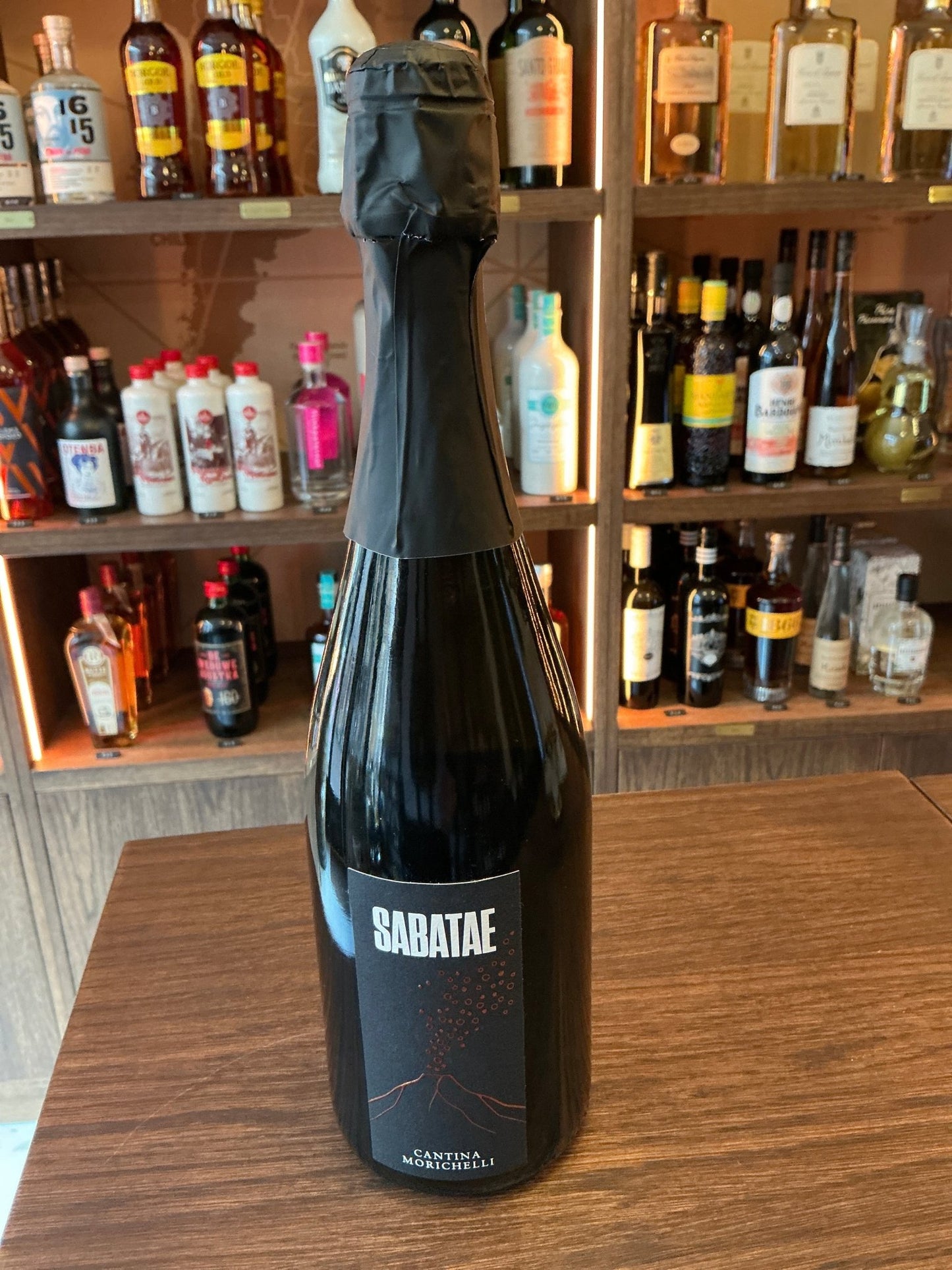 Sabatea Spumante premium sparkling wine bottle with black foil top on wooden table, artisan specialty spirits showcase in.