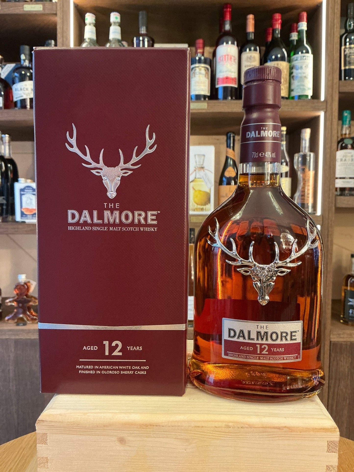 The Dalmore 12 Year premium single malt whisky bottle with signature stag emblem, amber aged spirit in clear glass beside.