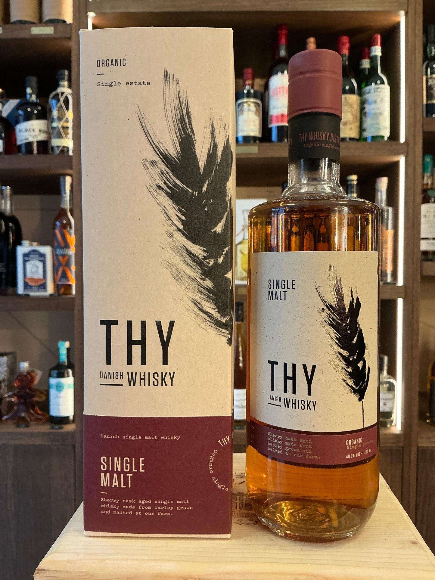 Thy Single Malt Organic Whisky bottle with amber liquid, botanical feather design on label and box, premium Dutch craft.