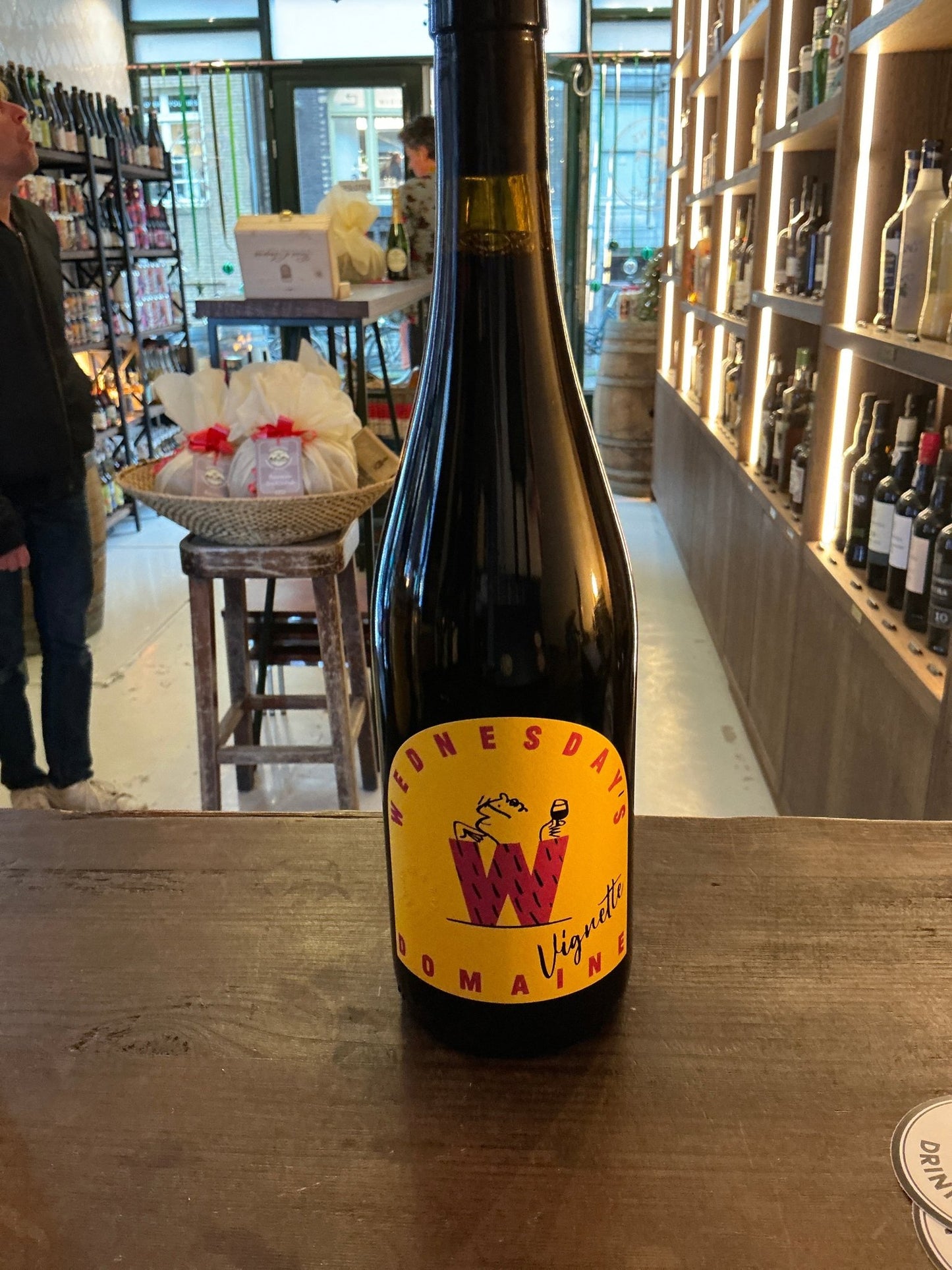 Wednesday’s Vignette premium non-alcoholic wine bottle with bright yellow label featuring red and purple botanical design on .