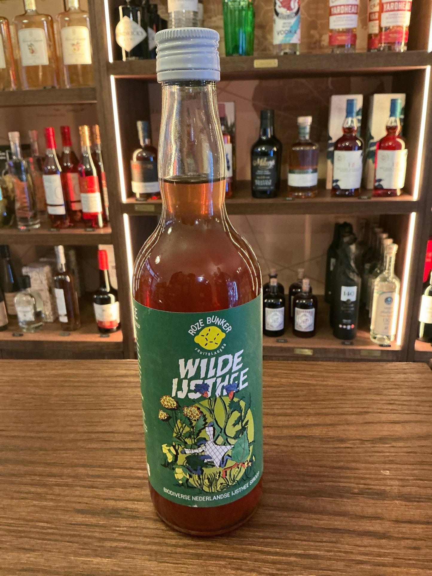 Wilde Ijsthee Big botanical cordial bottle with green label featuring floral design, artisan Dutch specialty spirit for.