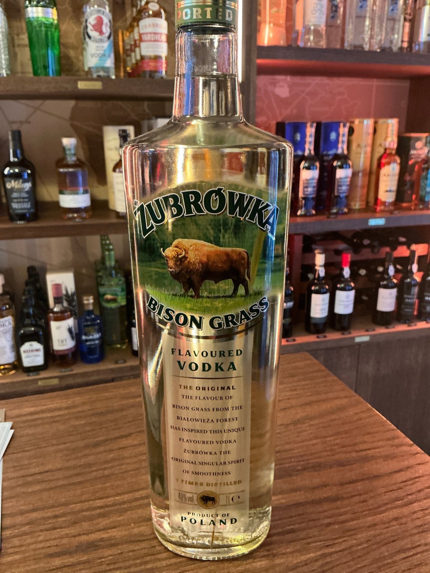 Tall clear bottle of Zubrowka Bison Grass Vodka with green label featuring a bison illustration, premium botanical flavored.