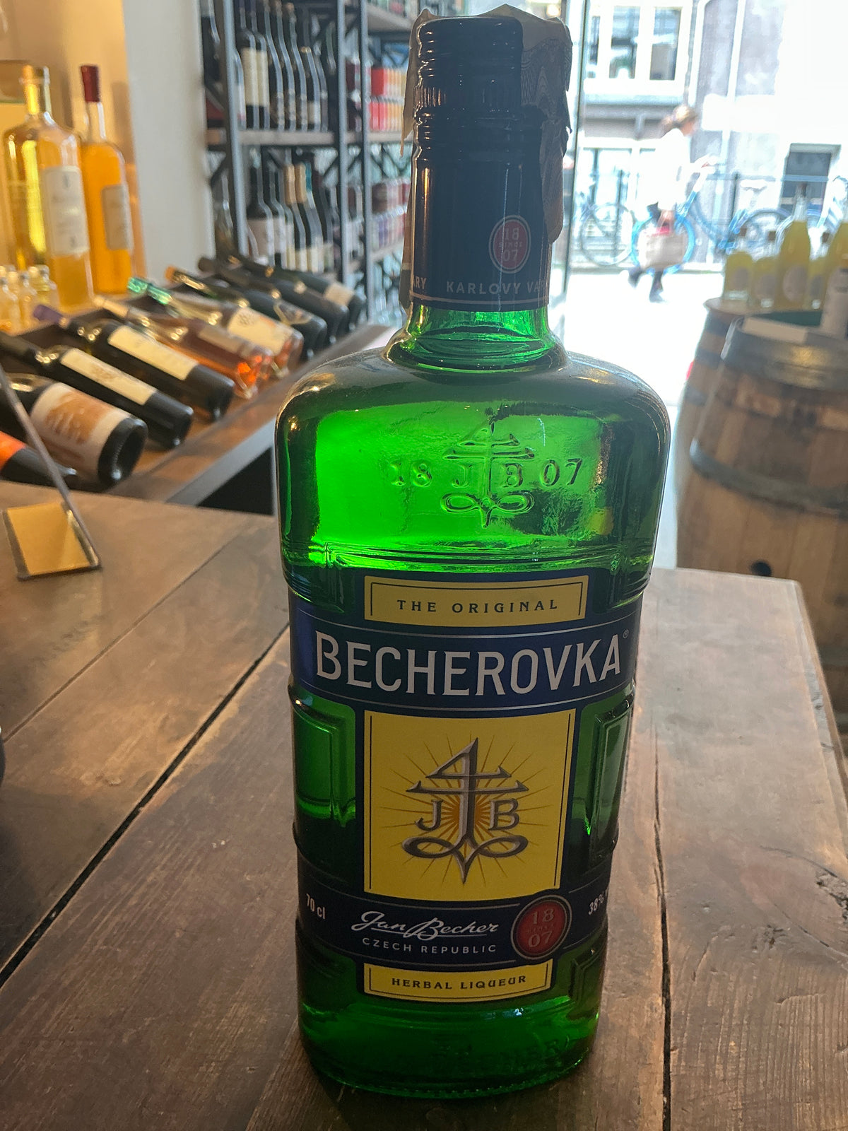 Green glass bottle of Karlsbader Becherovka herbal liqueur with black cap, Dutch artisanal design, botanical spiced label on .