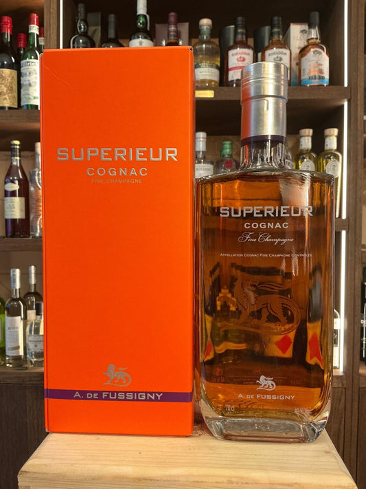 A. De Fussigny Superieur Fine Champagne Cognac bottle with amber liquid next to vibrant orange box, premium aged brandy in.