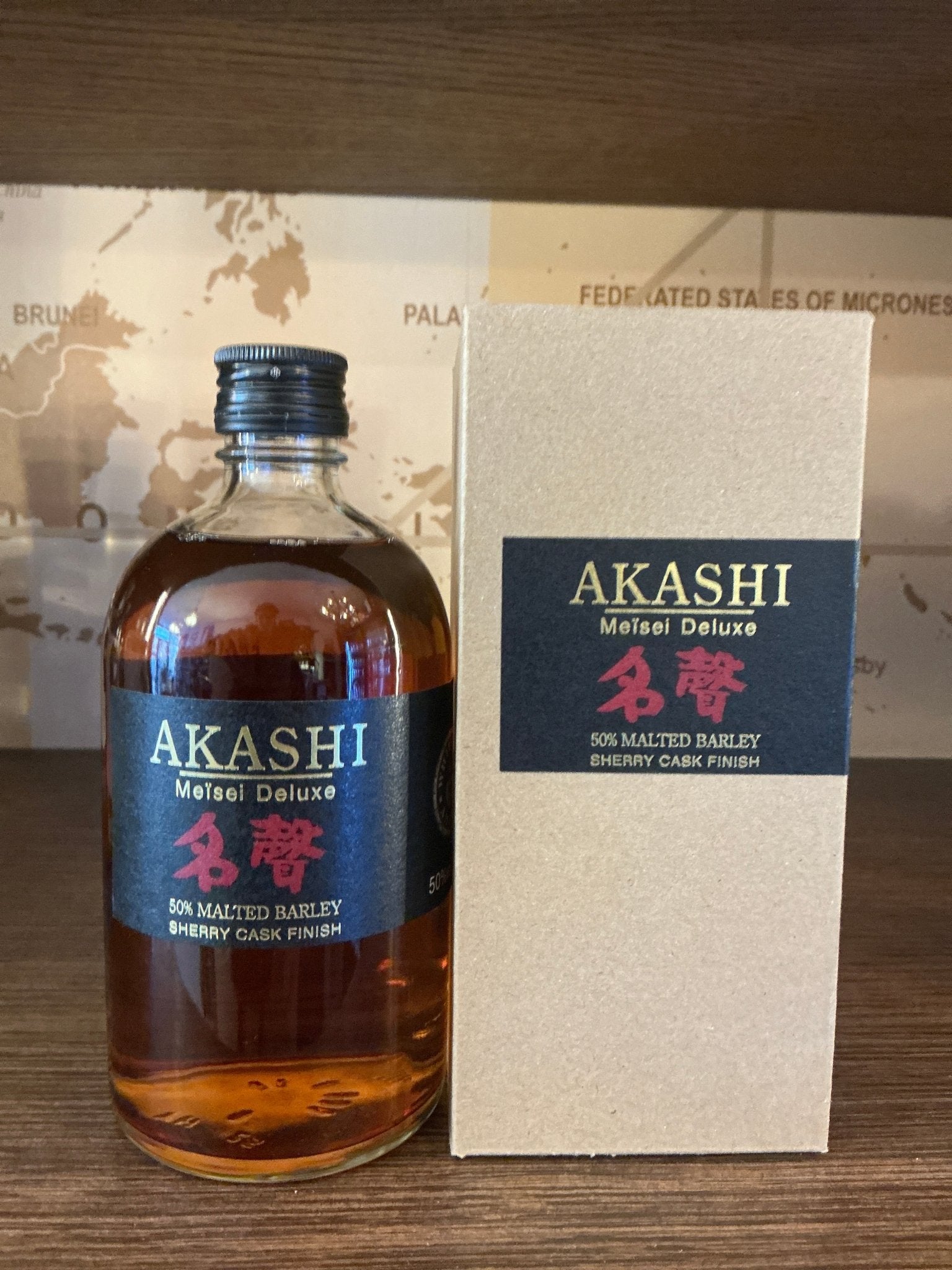 Akashi Meisei Deluxe Sherry Cask premium Japanese blended whisky bottle with dark amber liquid, black and red label, beside.