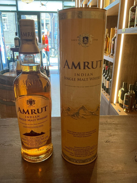 Amrut Single Malt Indian whisky bottle with amber liquid, next to a matching premium cylindrical box featuring artisan.