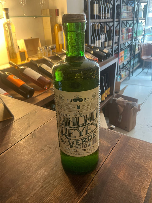 Tall green glass bottle of Ancho Reyes Verde spiced liqueur with detailed white label featuring bold black and green text,.