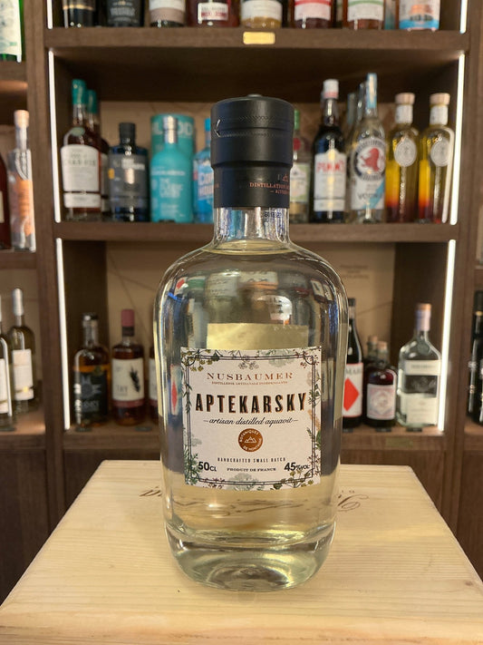 Aptekarsky Aquavit clear glass bottle with black cap, labeled premium distilled botanical spiced spirit on wooden surface.