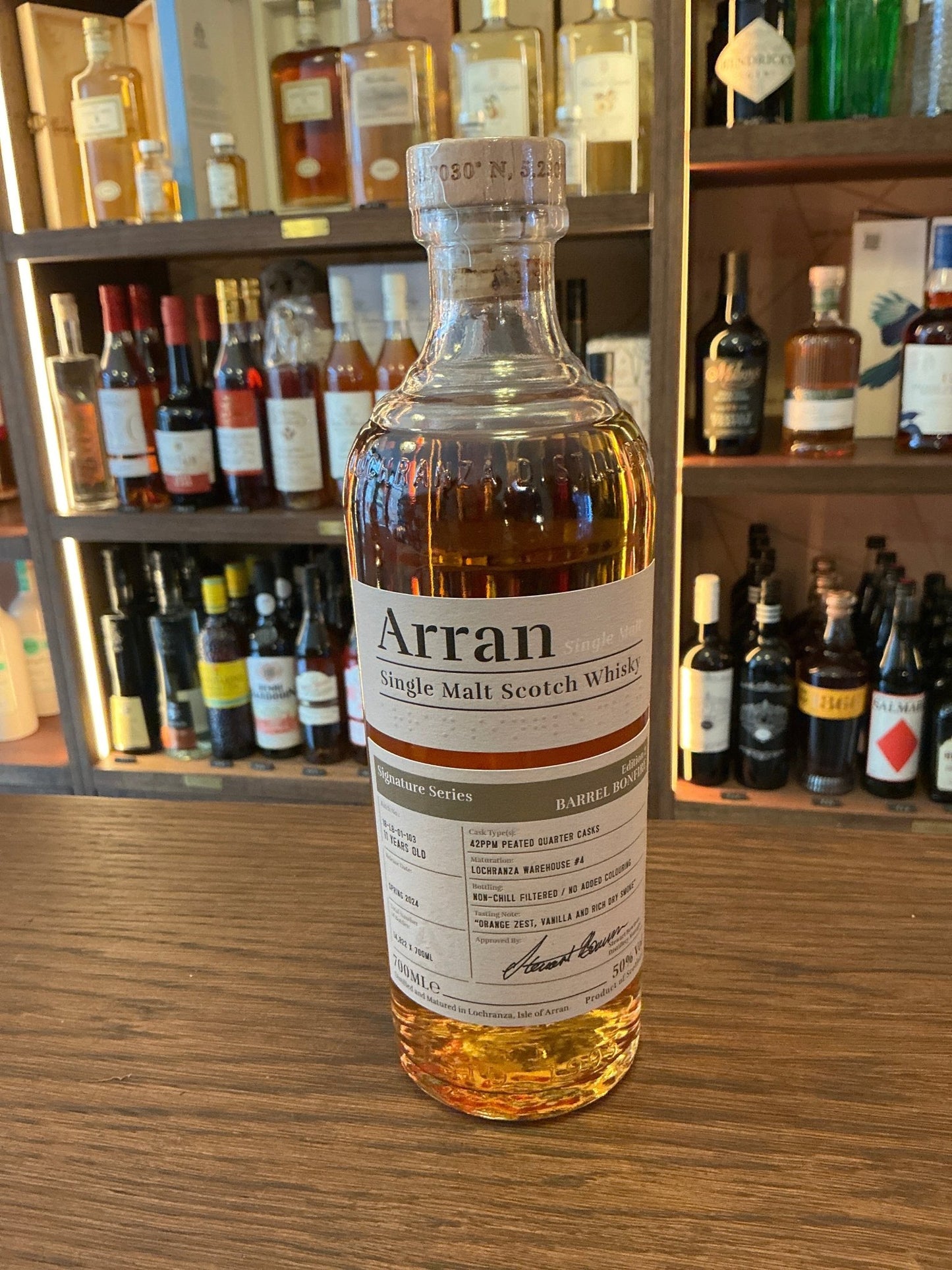 Arran Barrel Bonfire Edition 2 premium aged single malt whisky bottle with amber liquid and detailed label on wooden surface .