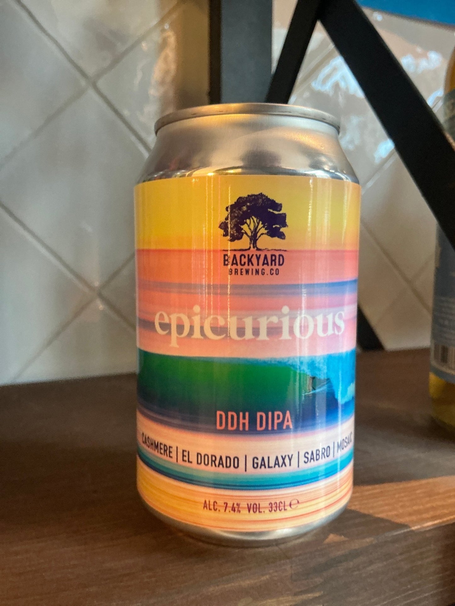 Backyard Brewing Epicurious DDH DIPA craft beer can with colorful gradient label featuring oranges, pinks, greens, and blues .