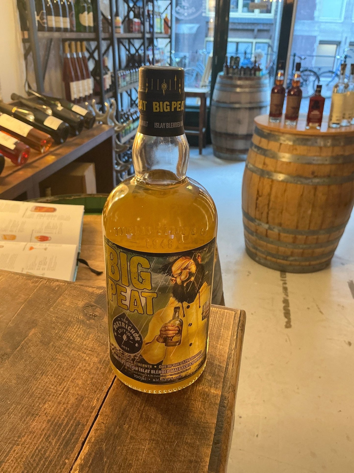 Big Peat The Peatrichor single malt whisky bottle with golden amber liquid in rustic distillery setting, premium small batch .