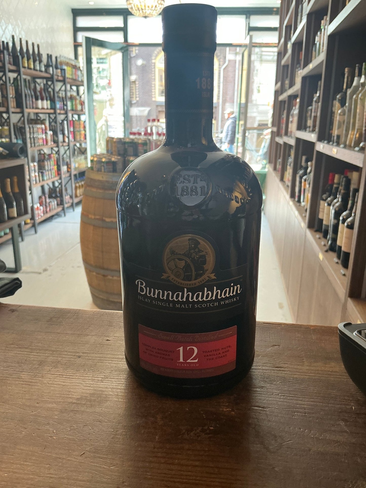 Bunnahabhain 12 Year Old premium Scottish single malt whisky bottle with aged, distilled, and artisanal qualities on wooden.
