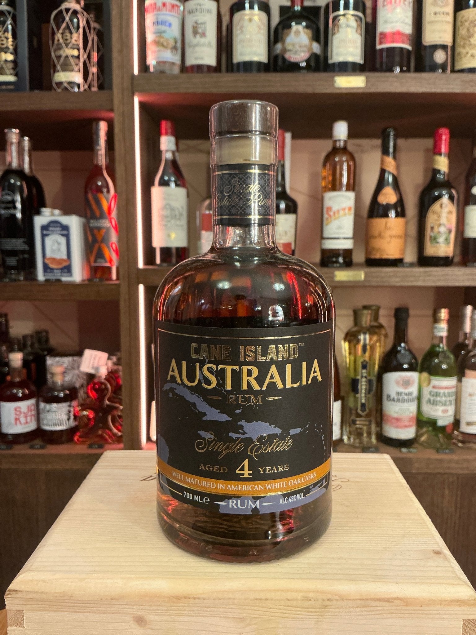 Cane Island Australia Single Estate Rum 4 Year aged potstill bottle with premium artisan label on wooden crate, surrounded.
