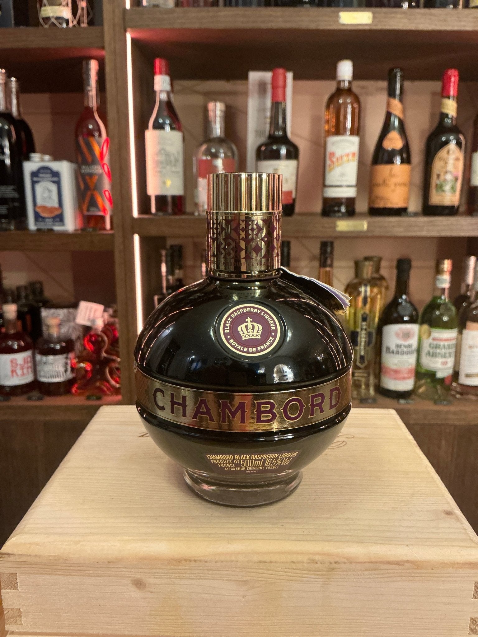 Round dark glass bottle of Chambord liqueur with gold and purple label, premium artisan raspberry liqueur in specialty.