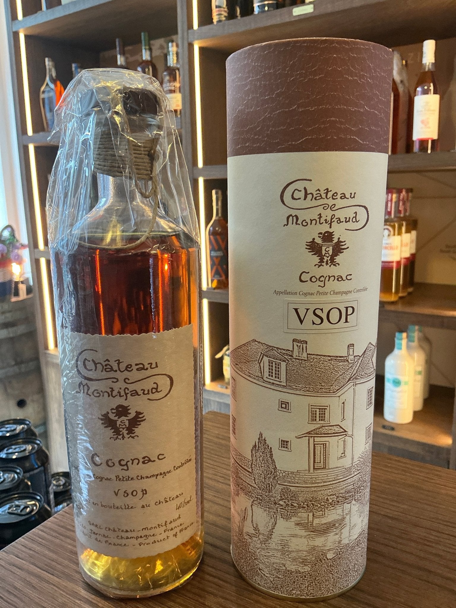 Chateau de Montifaud VSOP Millenium Cognac bottle with amber liquid, alongside textured cylindrical brown and beige box.