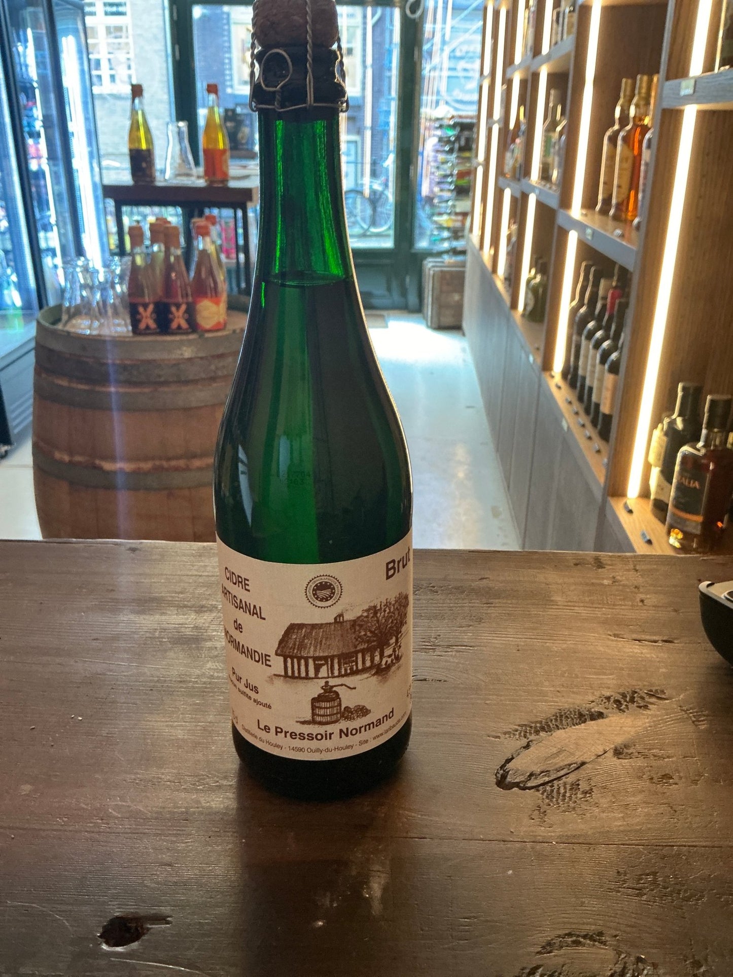 Cidre Artisanal de Normandie Brut Le Houley green glass bottle with white label featuring rustic scene, premium small batch.