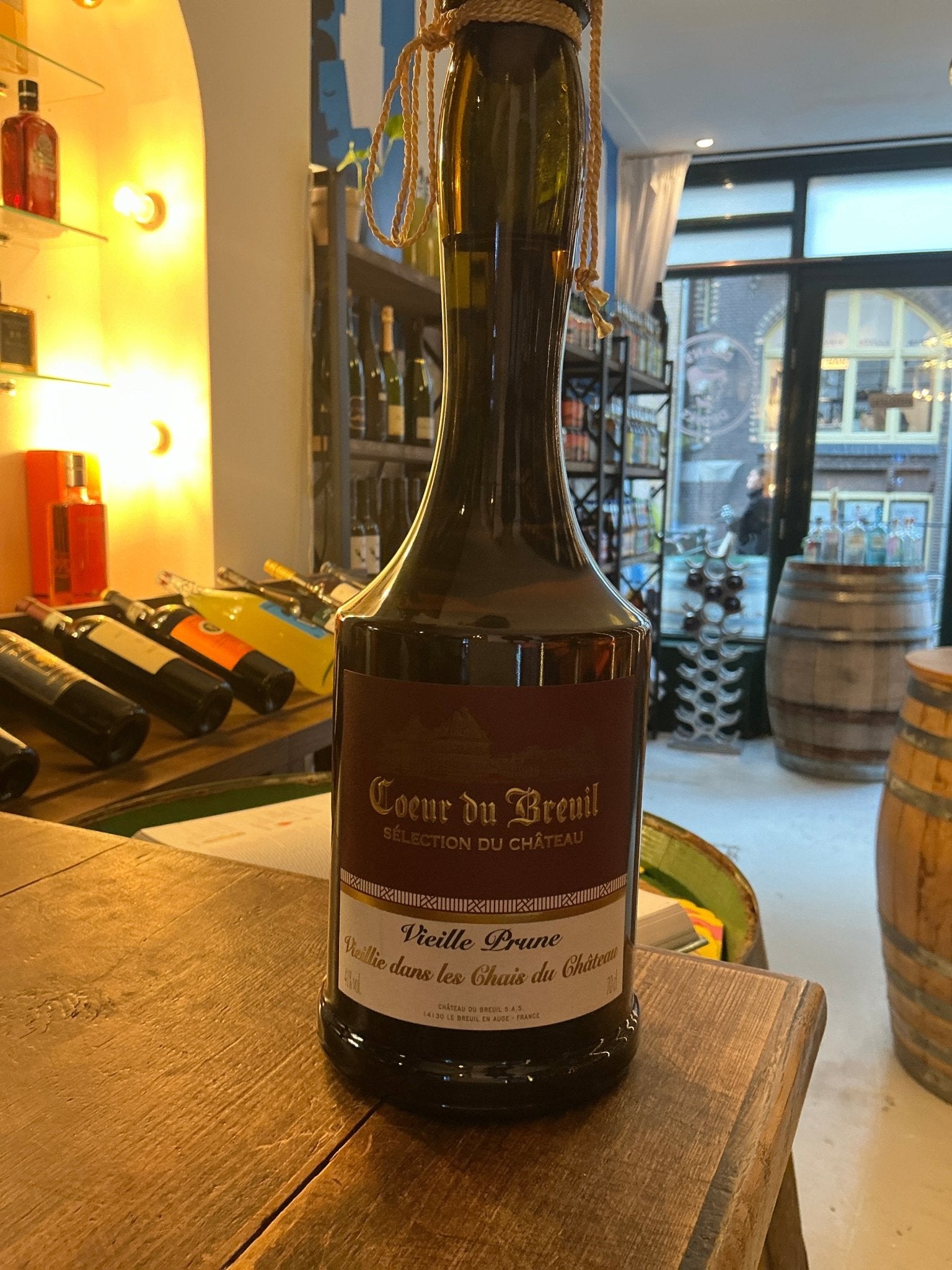 Coeur du Breuil Vieille Prune plum brandy bottle with dark glass and vintage label on rustic wooden table in artisan spirits .