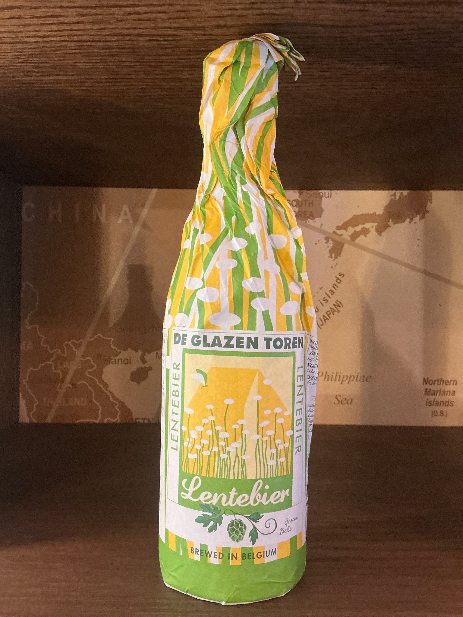 De Glazen Toren Lentebier craft beer bottle wrapped in green and yellow botanical-themed paper, artisan Dutch small batch.