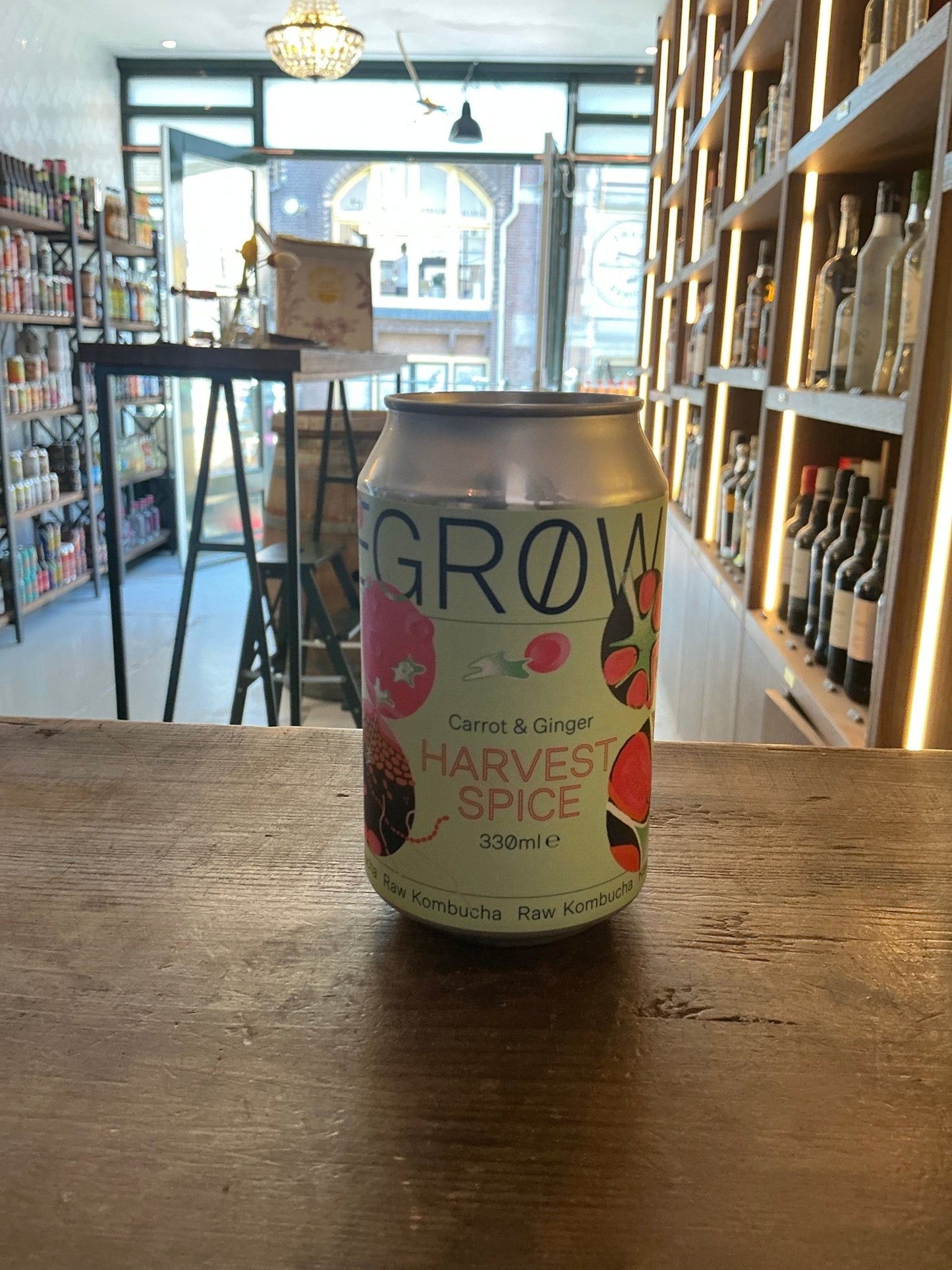 Degrow Lab Harvest Spice canned kombucha with carrot and ginger botanical infusion on wooden table in artisan beverage shop.