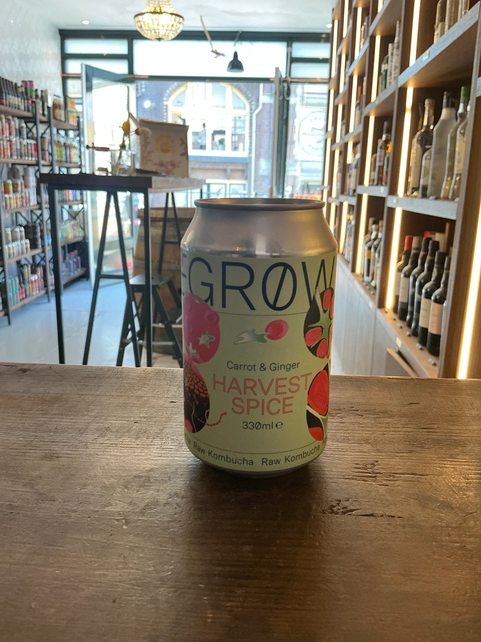 Degrow Lab Harvest Spice canned kombucha with carrot and ginger botanical infusion on wooden table in artisan beverage shop.